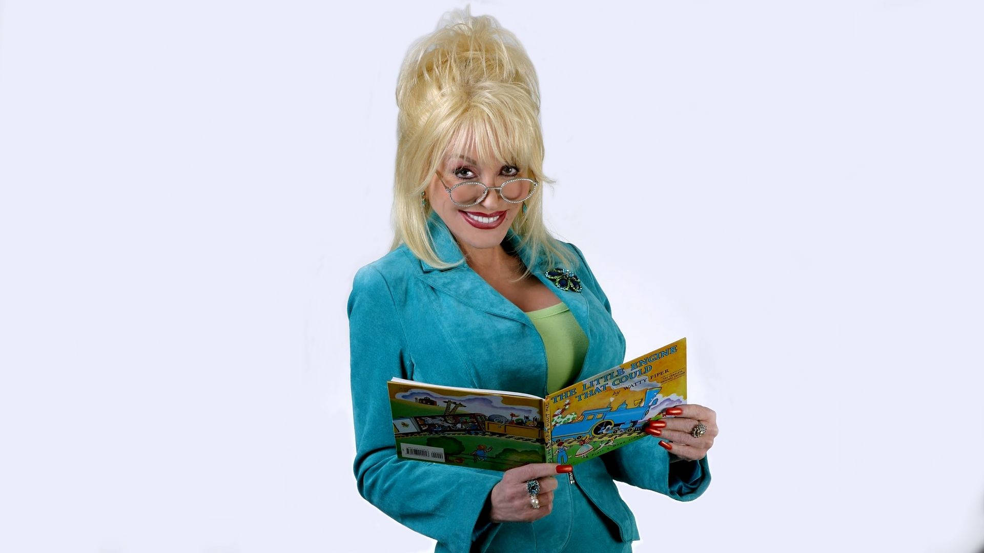 多莉·帕頓手持書本 壁紙 — Dolly Parton 喺純白背景前溫暖咁微笑，手上揸住一本打開嘅兒童書。