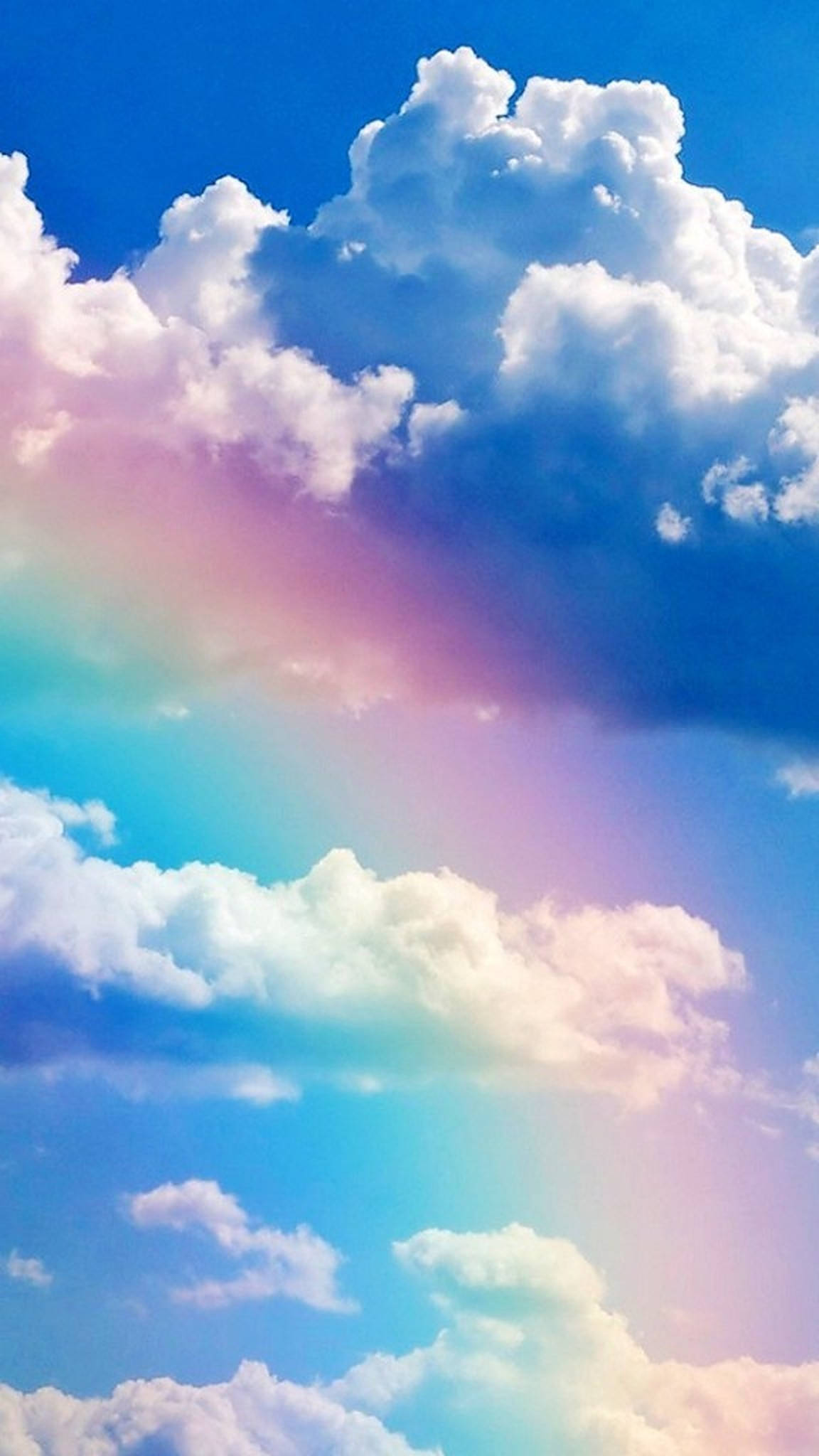 多雲天氣與彩虹 壁紙 — 充滿活力的粉彩彩虹穿過蓬鬆的白雲，映襯著鮮豔的藍天。
