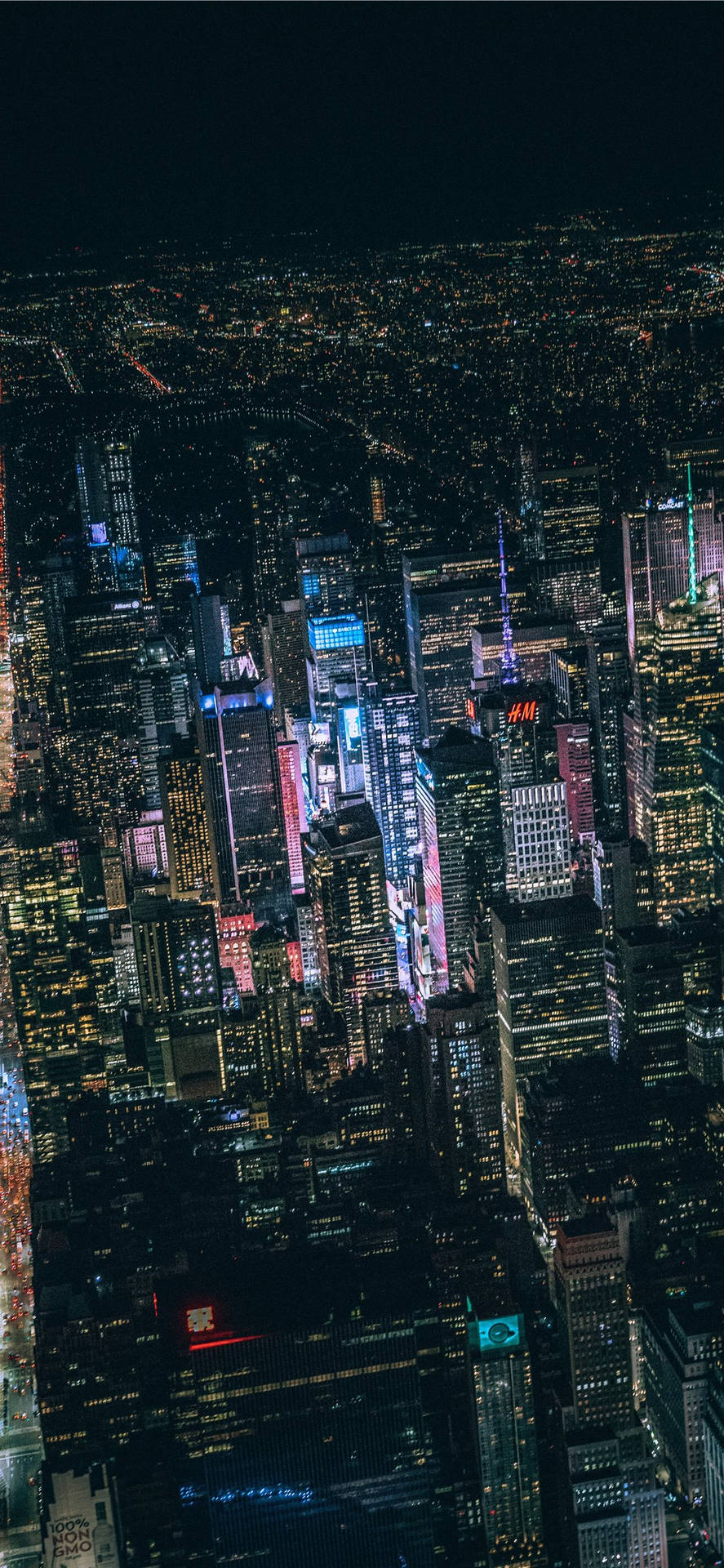 夜晚密集的城市天際線鳥瞰圖，建築物和霓虹燈閃閃發光。