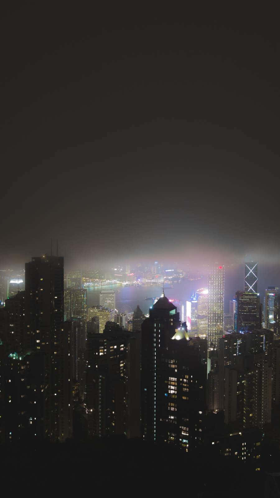 夜城絢麗的夜景 壁紙 — 密集城市天際線的朦朧夜景，閃爍的摩天大樓和霧氣瀰漫的地平線。