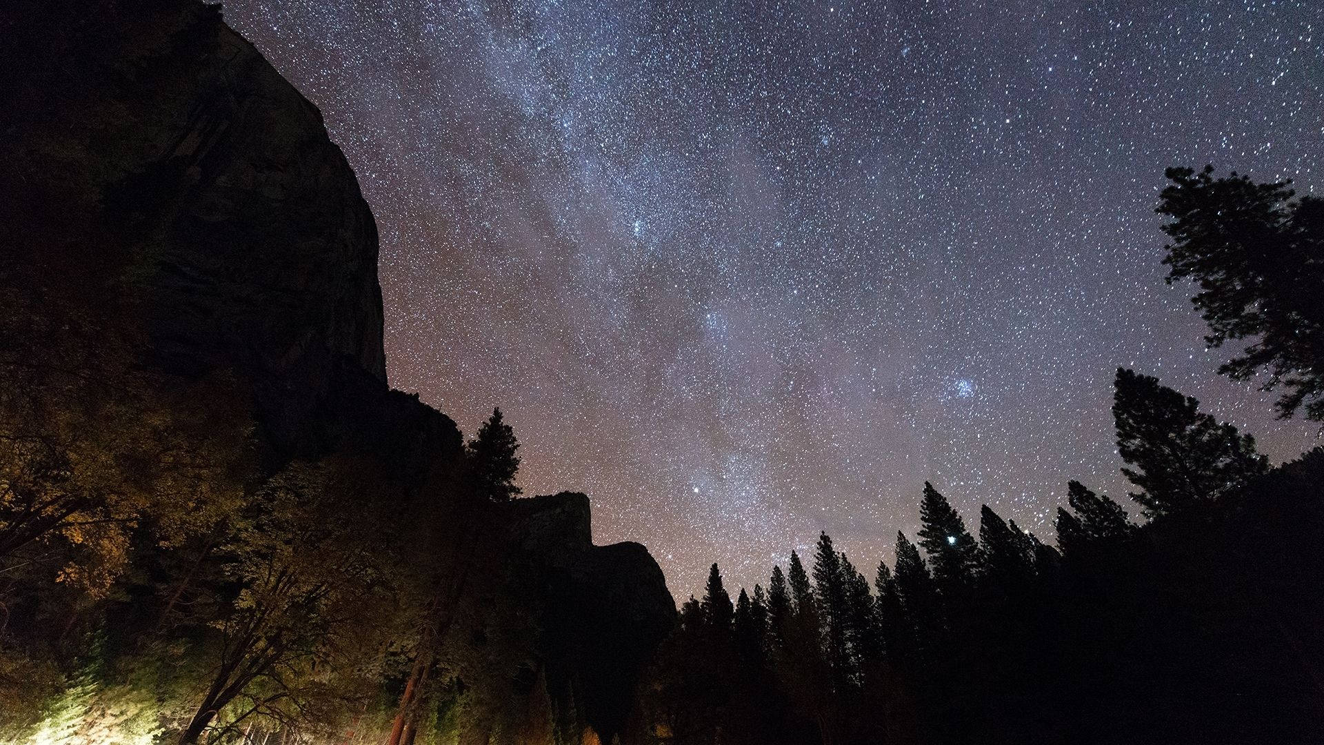 在星空下，黑暗的森林和岩石形成，銀河可見。