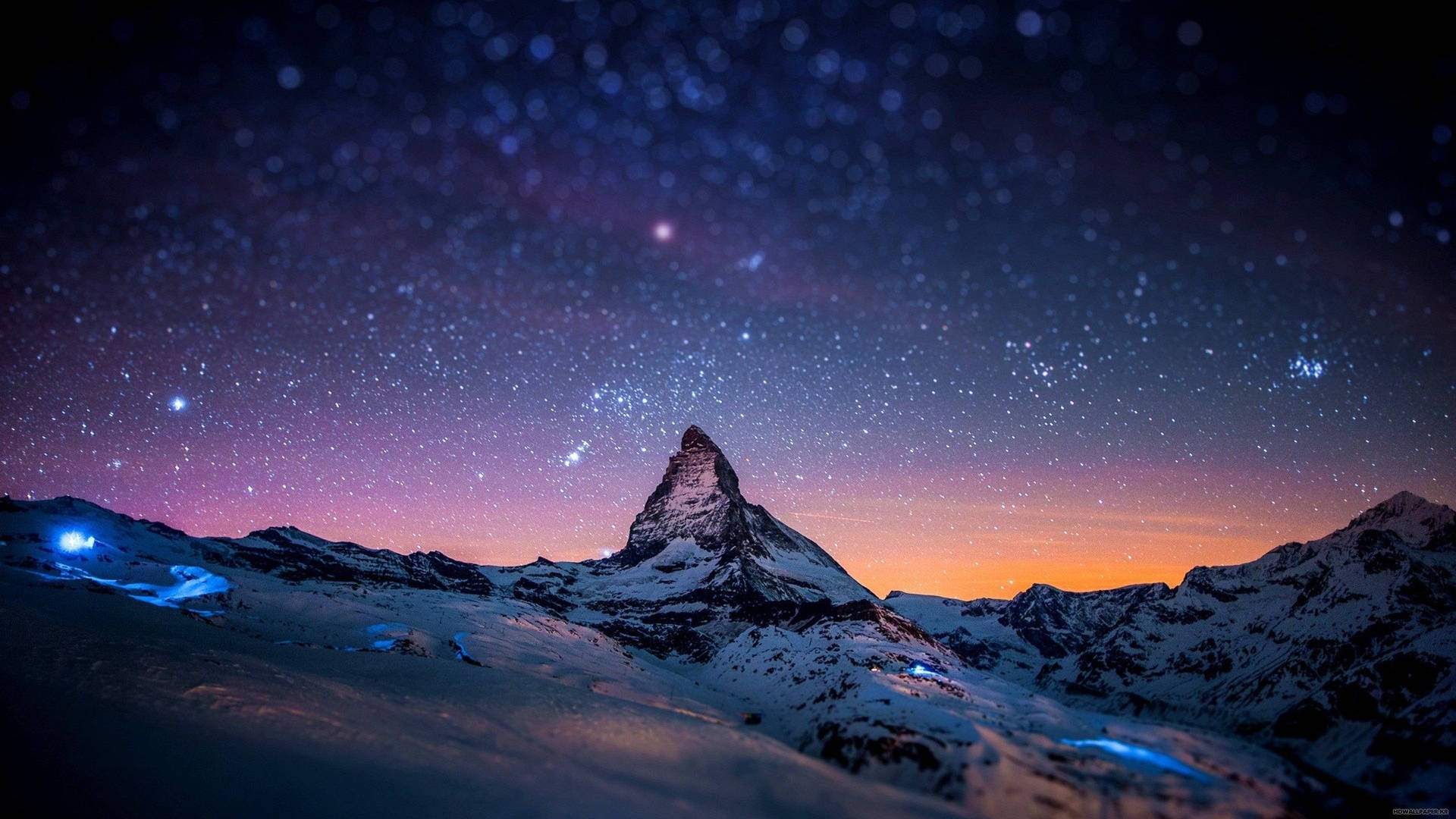 星空暮色下的雪山峰頂，下方有發光的藍色燈光