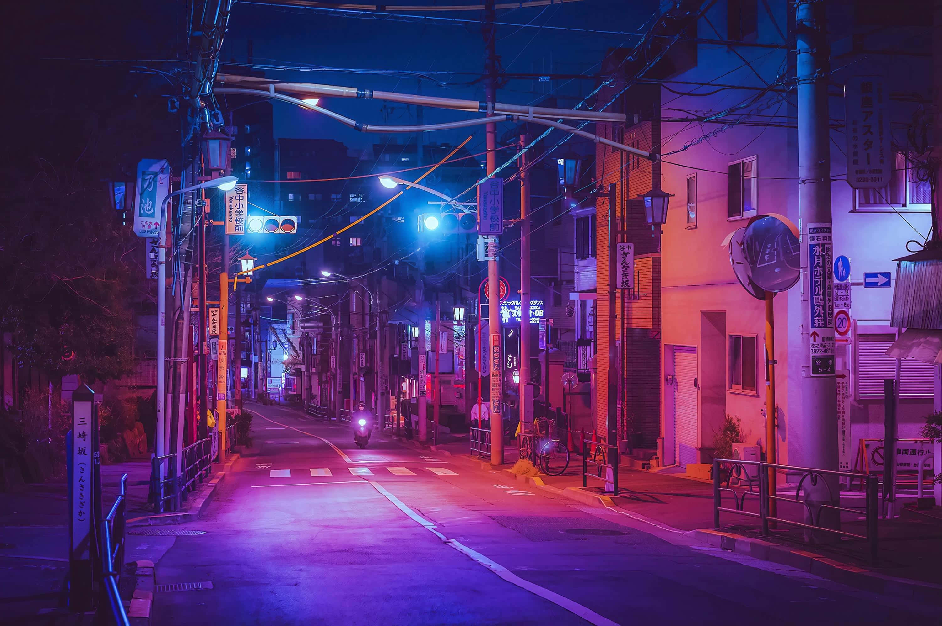 Aesthetic Anime City 桌布 壁紙 — 夜晚一條充滿霓虹燈的日本小巷，粉紅色和藍色的燈光在潮濕的路面上反射。