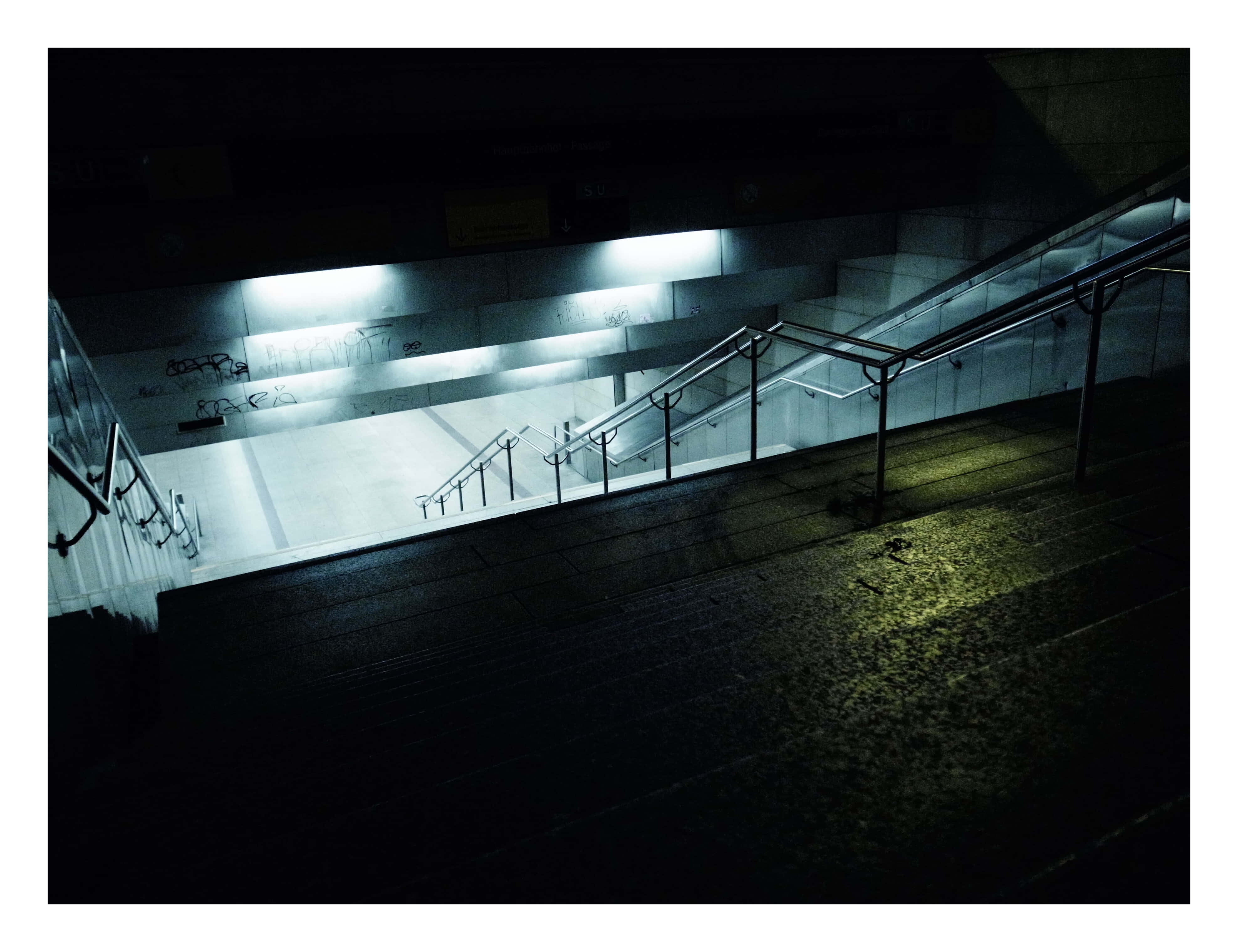 Dark Underground 桌布 壁紙 — 夜晚一條燈光昏暗的混凝土樓梯，強烈的螢光燈投下長長的陰影，牆上有塗鴉。