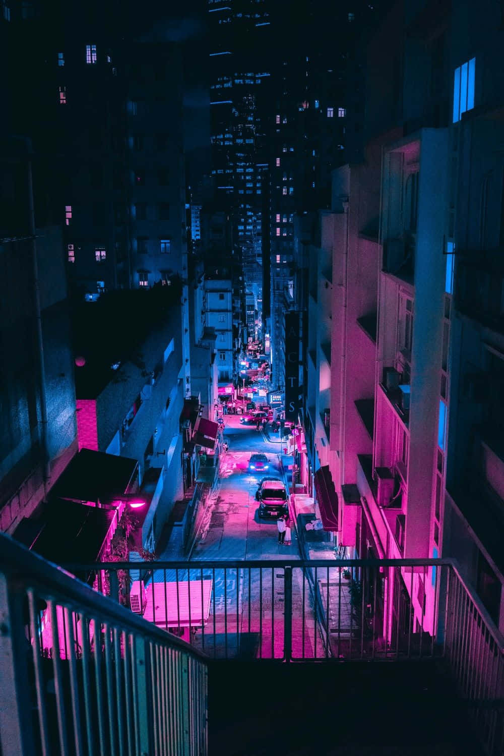 螢光藍 桌布 壁紙 — 夜晚一條狹窄的城市小巷，沐浴在鮮豔的粉紅和藍色霓虹燈光中，燈光反射在濕漉漉的路面上。