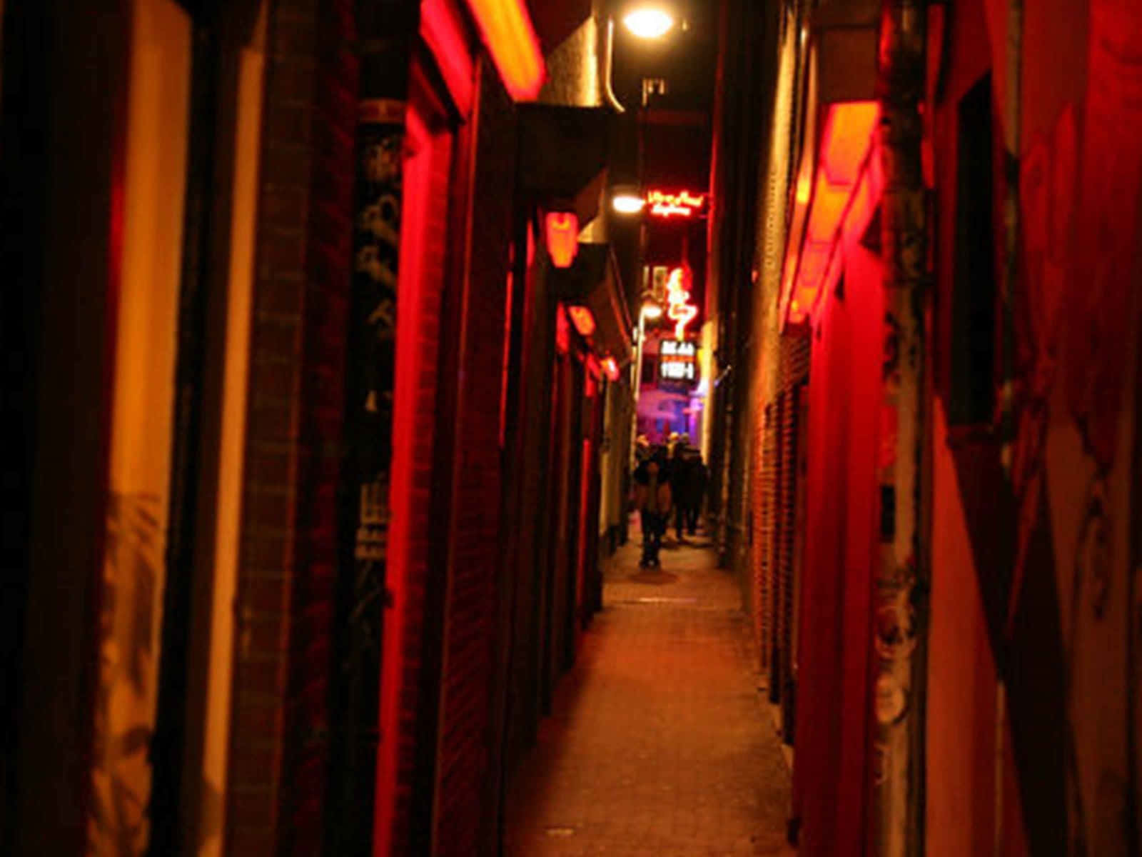 Red Light District 桌布 壁紙 — 夜晚一條狹窄的小巷沐浴在溫暖的紅色霓虹燈光中，有剪影人物走向遠方。