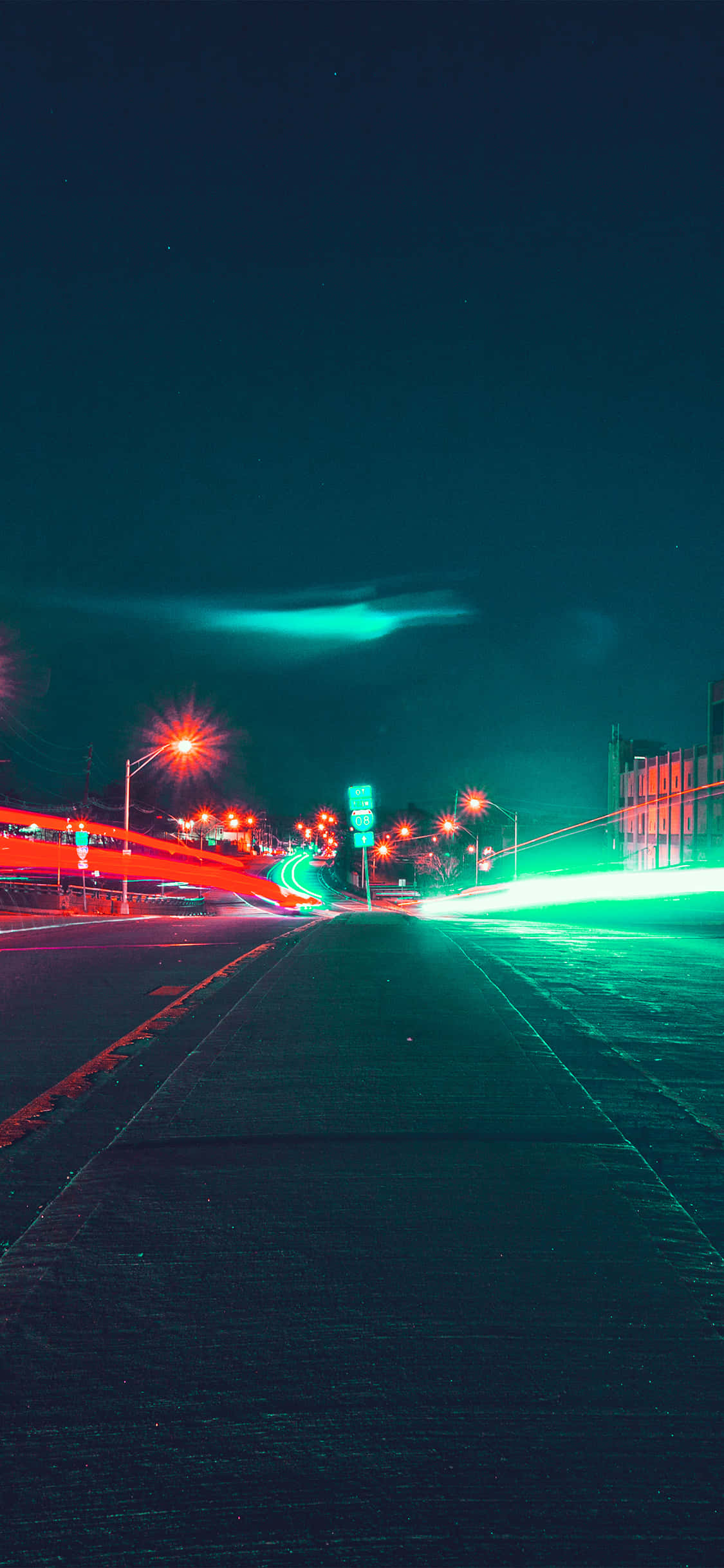 Night Street 桌布 壁紙 — 夜晚一條被霓虹燈照亮的城市道路，在黑暗的天空下，移動的車輛留下紅色和綠色的光跡。