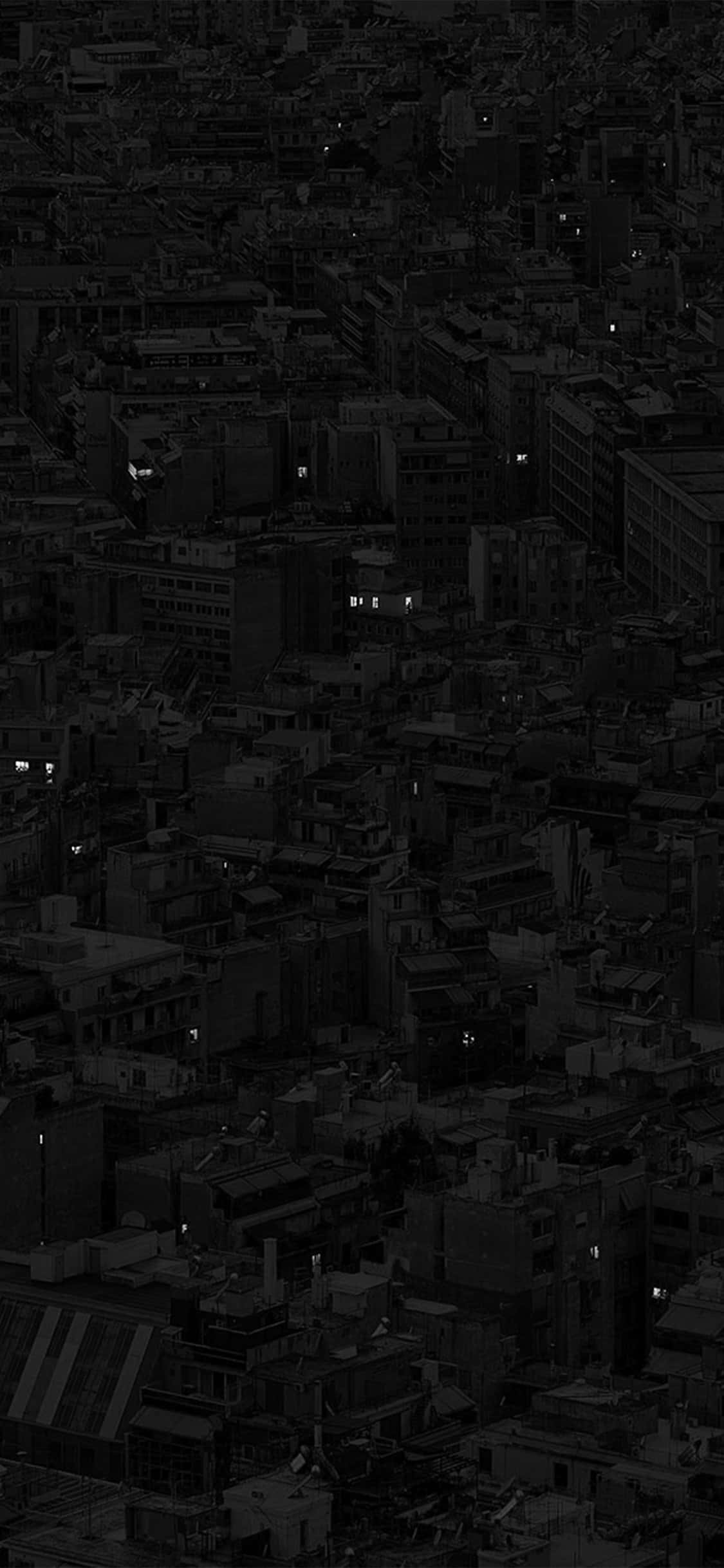 深色iPhone壁紙 桌布 壁紙 — 夜晚密集城市的鳥瞰圖，散落的發光窗戶穿透黑暗的城市擴展區。