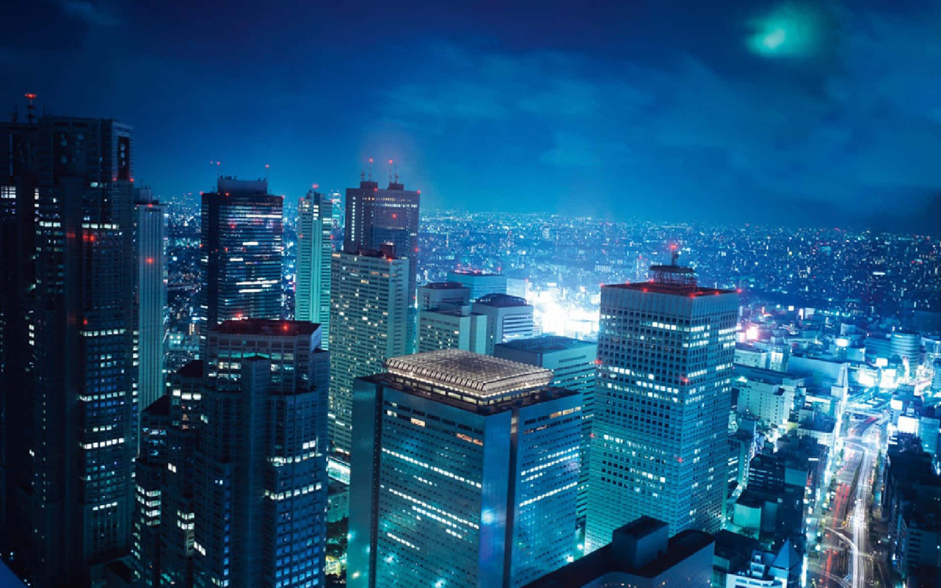 東京 桌布 壁紙 — 夜晚廣闊城市的鳥瞰圖，高聳的摩天大樓在深藍色天空下閃耀。