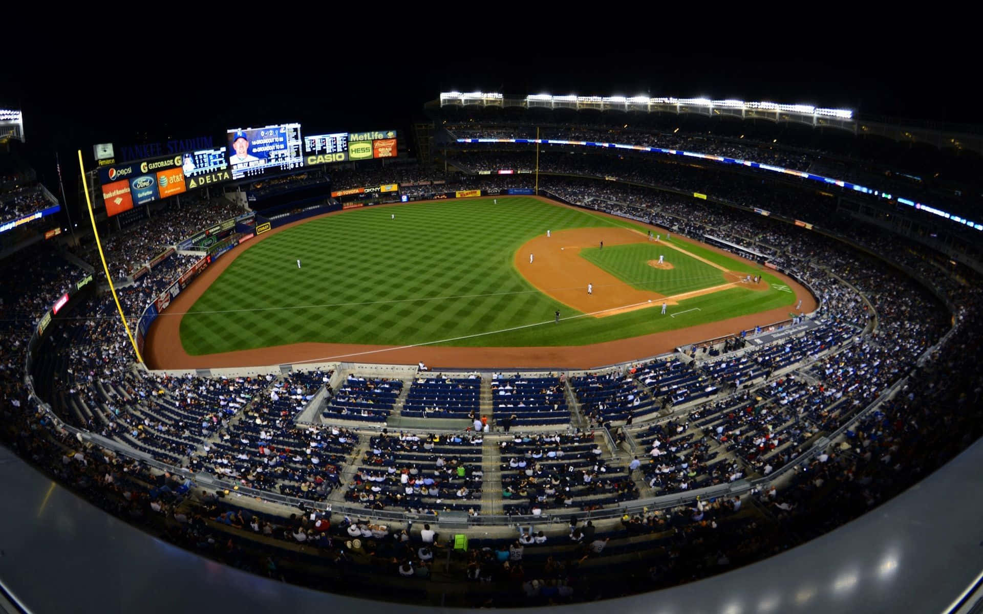 Baseball Stadium 桌布 壁紙 — 夜晚擠滿人的棒球場的廣角魚眼視圖，明亮的燈光照亮綠色球場和歡呼的球迷。