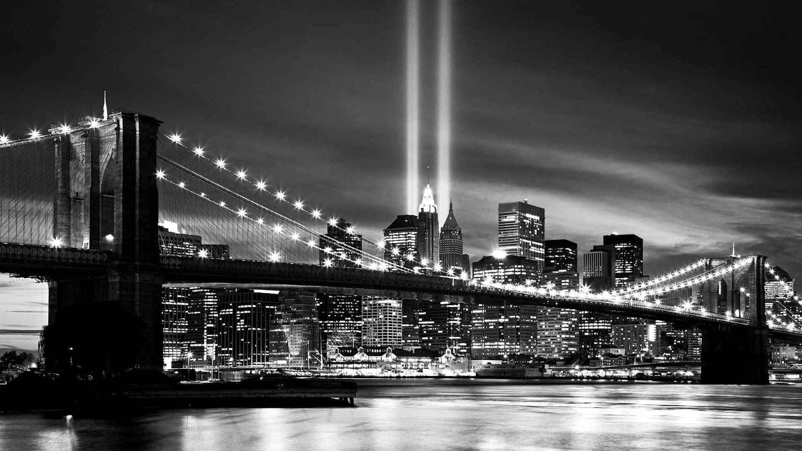 Black And White Cityscape 桌布 壁紙 — 夜晚的布魯克林大橋，雙子塔紀念光束照亮紐約天際線，黑白風格。