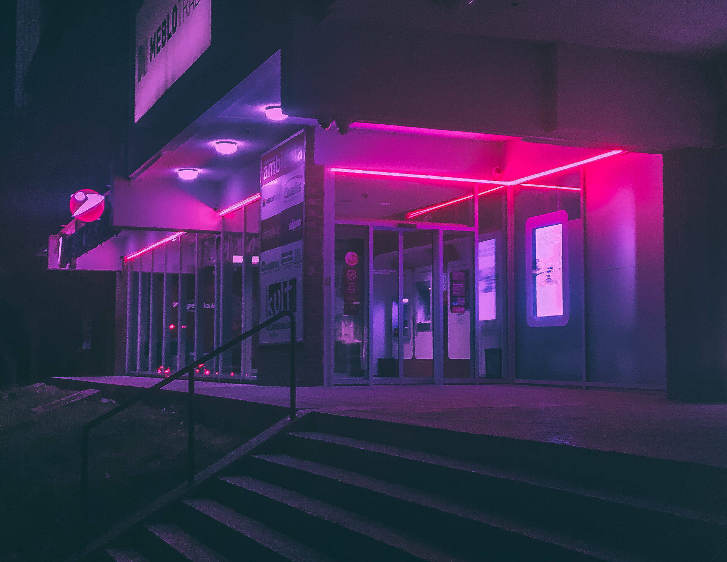 lights 桌布 壁紙 — 夜晚的現代建築入口沐浴在充滿活力的粉紅色霓虹燈中，在潮濕的人行道和玻璃門上投射出超現實的光芒。