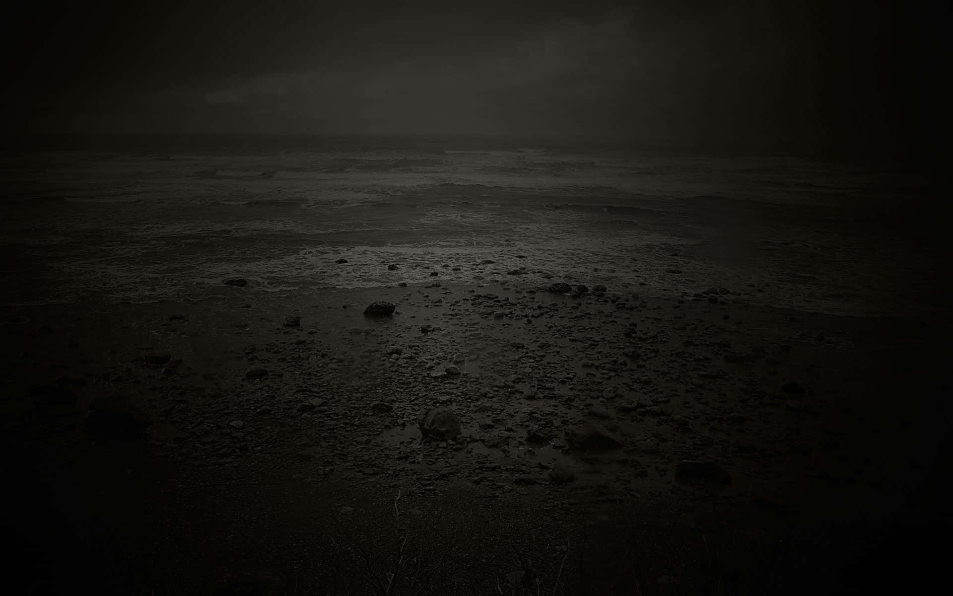憂鬱 桌布 壁紙 — 夜晚荒涼的黑暗海灘，濕沙岩石，濃雲下霧氣瀰漫的地平線。