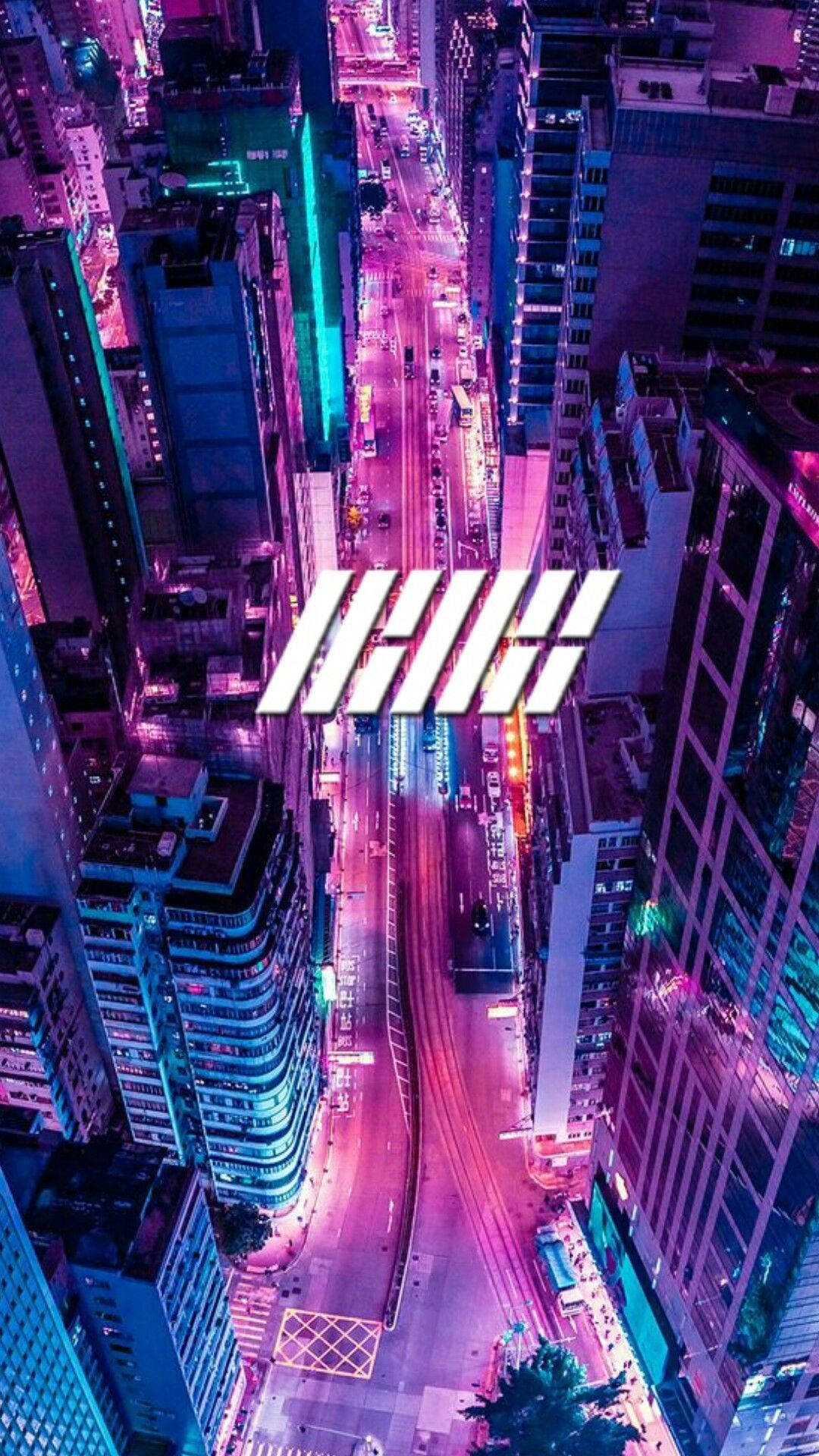 Building 桌布 壁紙 — 夜晚霓虹燈閃爍的城市街道鳥瞰圖，鮮豔的粉紅色和藍色燈光照亮高聳的建築物和流動的交通。