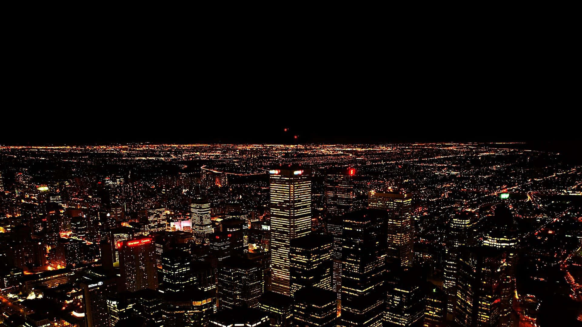 夜景城市風光 壁紙 — 從高空俯瞰夜晚中燈火通明的廣闊城市，無數發光的窗戶和街燈映襯著漆黑的天空。