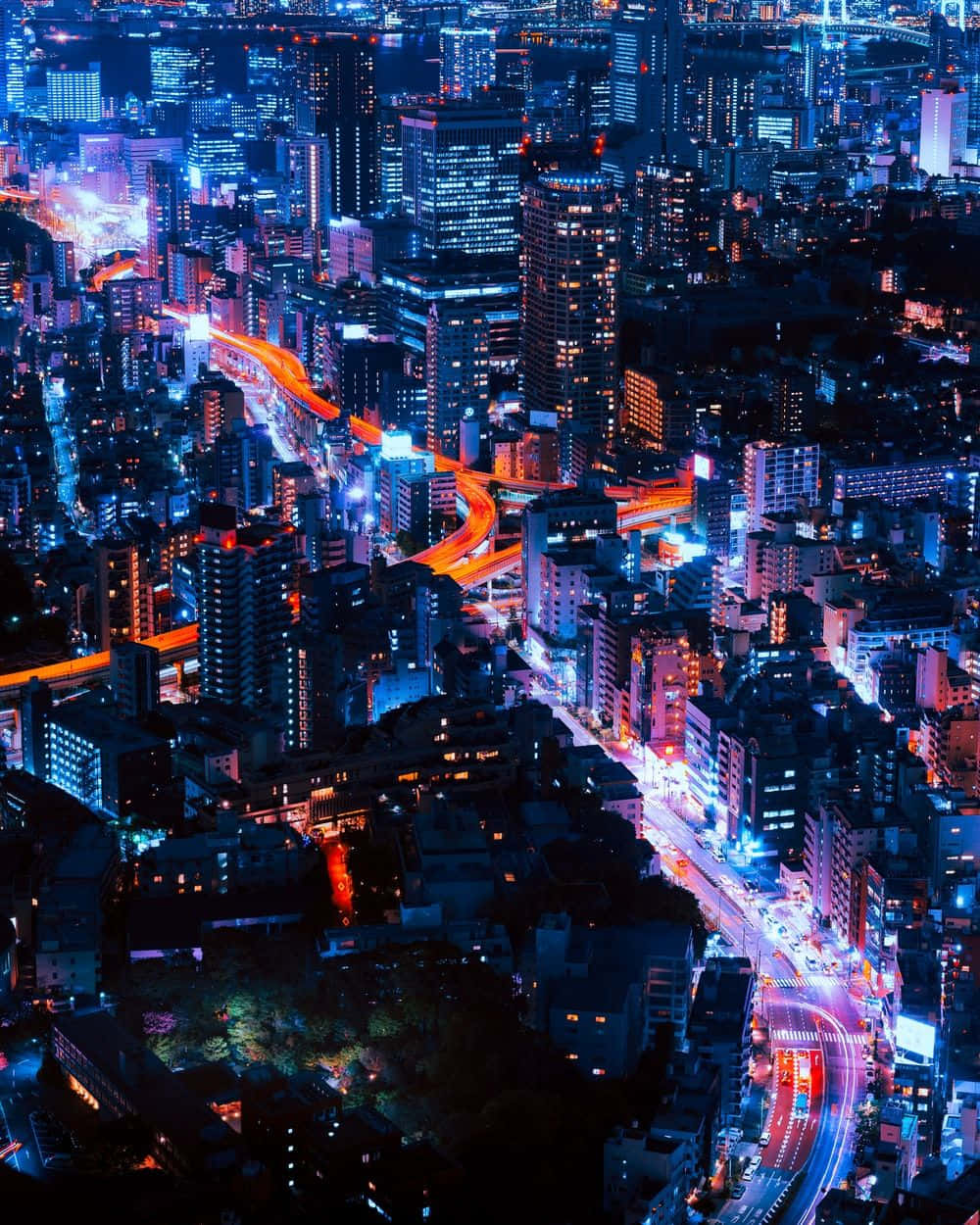 充滿活力的城市夜間鳥瞰圖，發光的道路和高樓大廈。