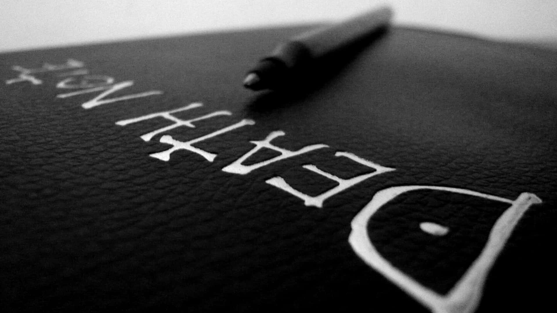 一本名為 Death Note 的黑色皮面筆記本，上面放著一支筆。