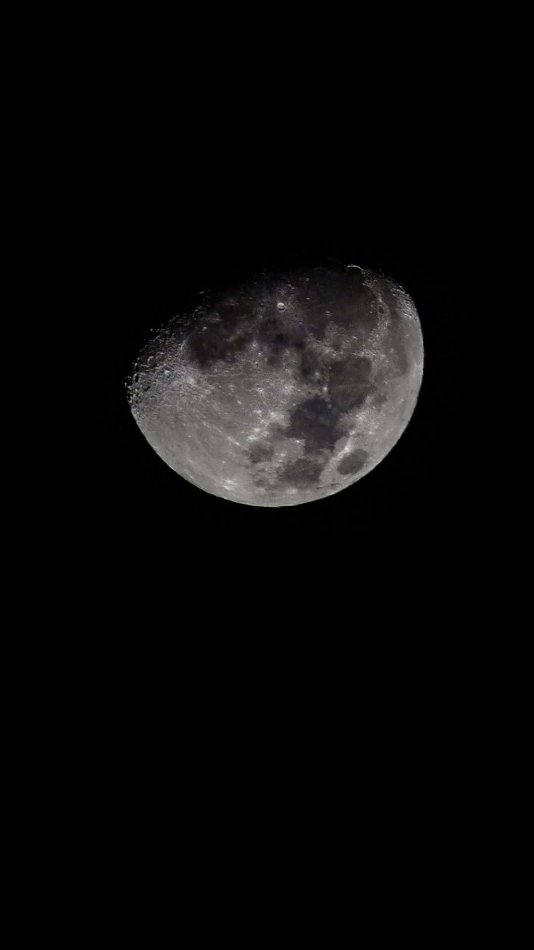 夜空中的宇宙，盡在你的黑色iPhone 壁紙 — 一個詳細的彎月，帶有可見的隕石坑和月海，在漆黑的夜空中柔和地發光。