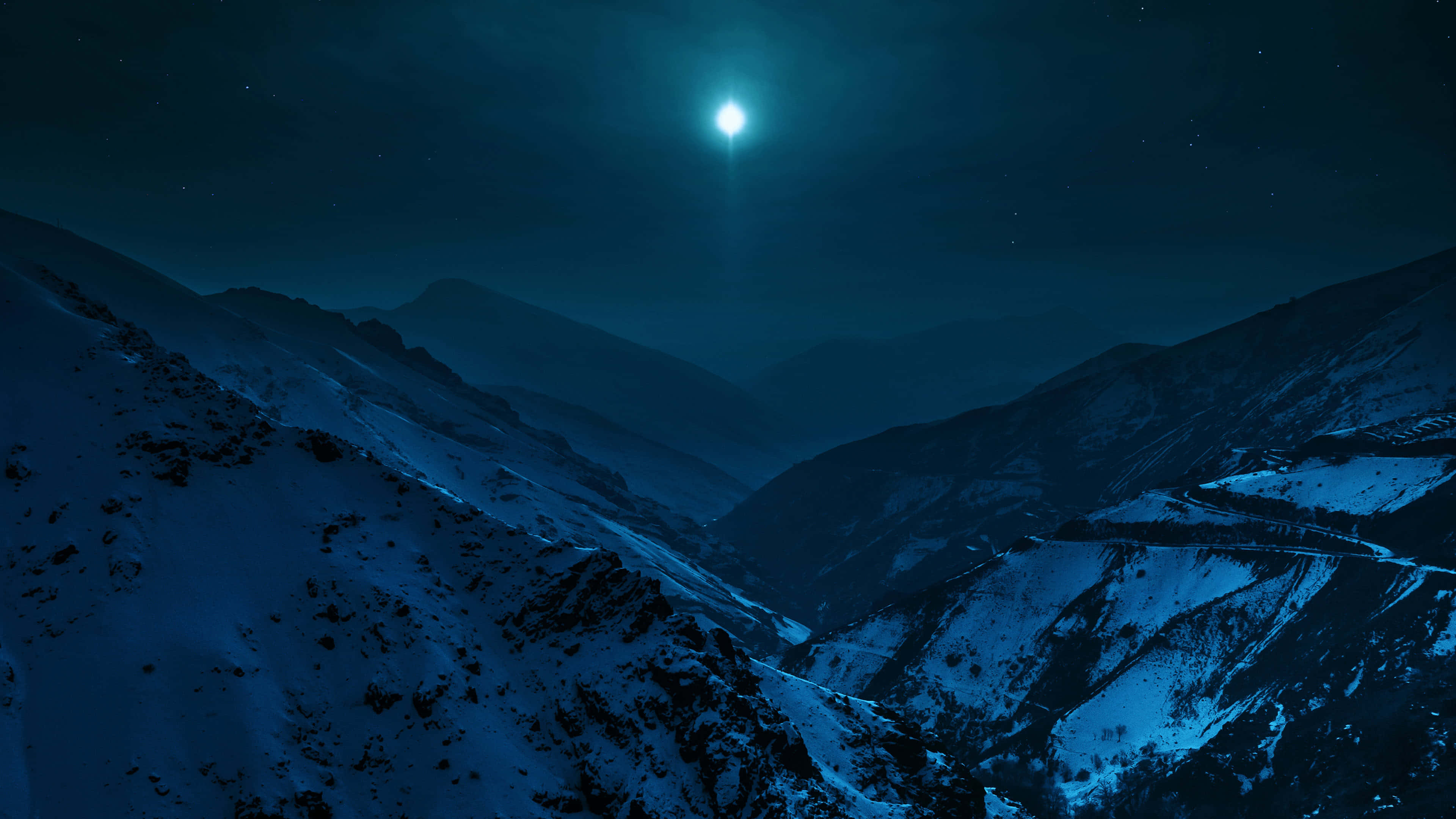夜空中的月亮 壁紙 — 一個被白雪覆蓋的山谷，沐浴在明亮月亮的冷光下，星空璀璨。