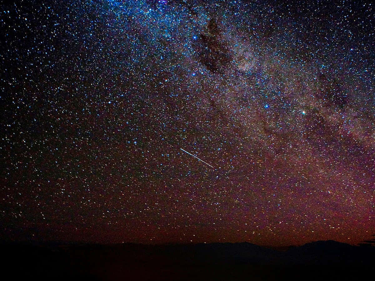 黑暗地平線上方有銀河和流星的星空夜空。