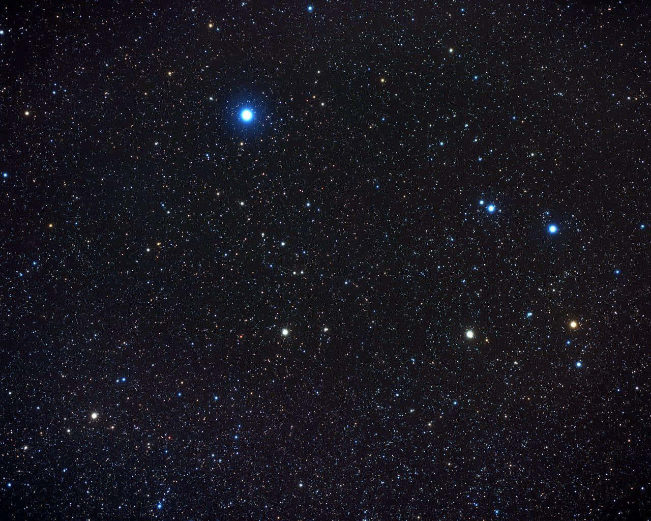 夜空的壯麗 壁紙 — 深邃的黑色天空佈滿無數閃爍的星星，包括一顆突出的明亮藍色星星。