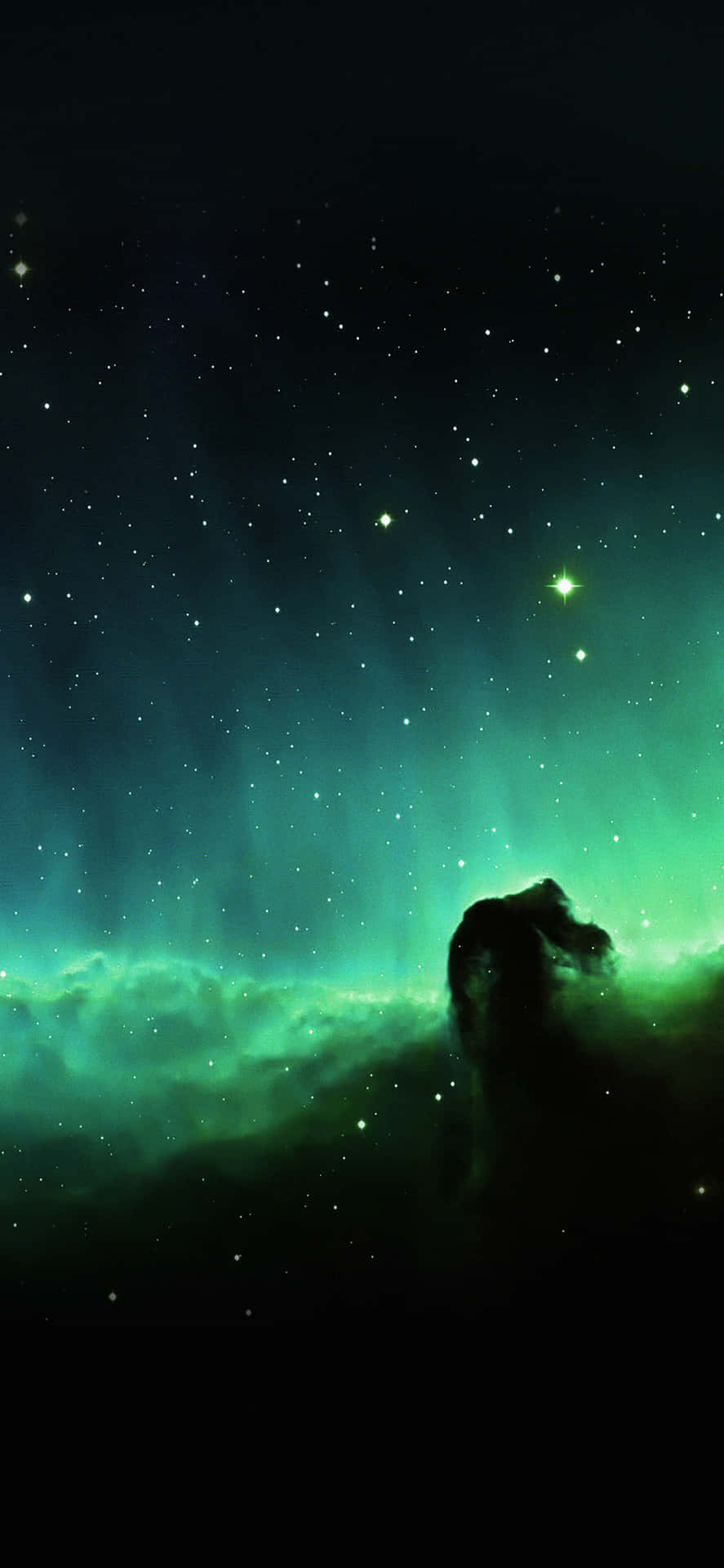 在繁星點點的夜空下，一個發光的綠色星雲與黑暗的宇宙輪廓。