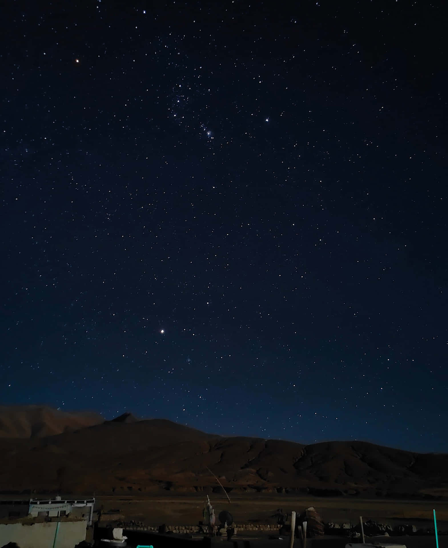 黑暗的山脈和一個村莊在星空下。