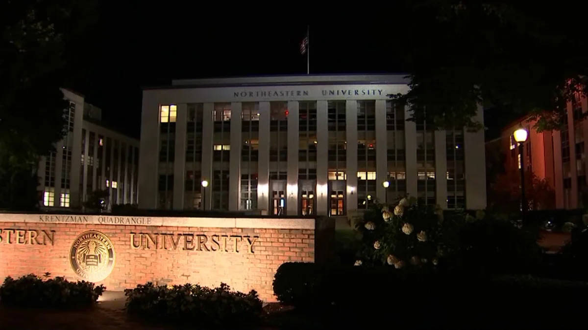 夜晚的東北大學建築物，帶有磚砌標誌和開花的灌木叢。