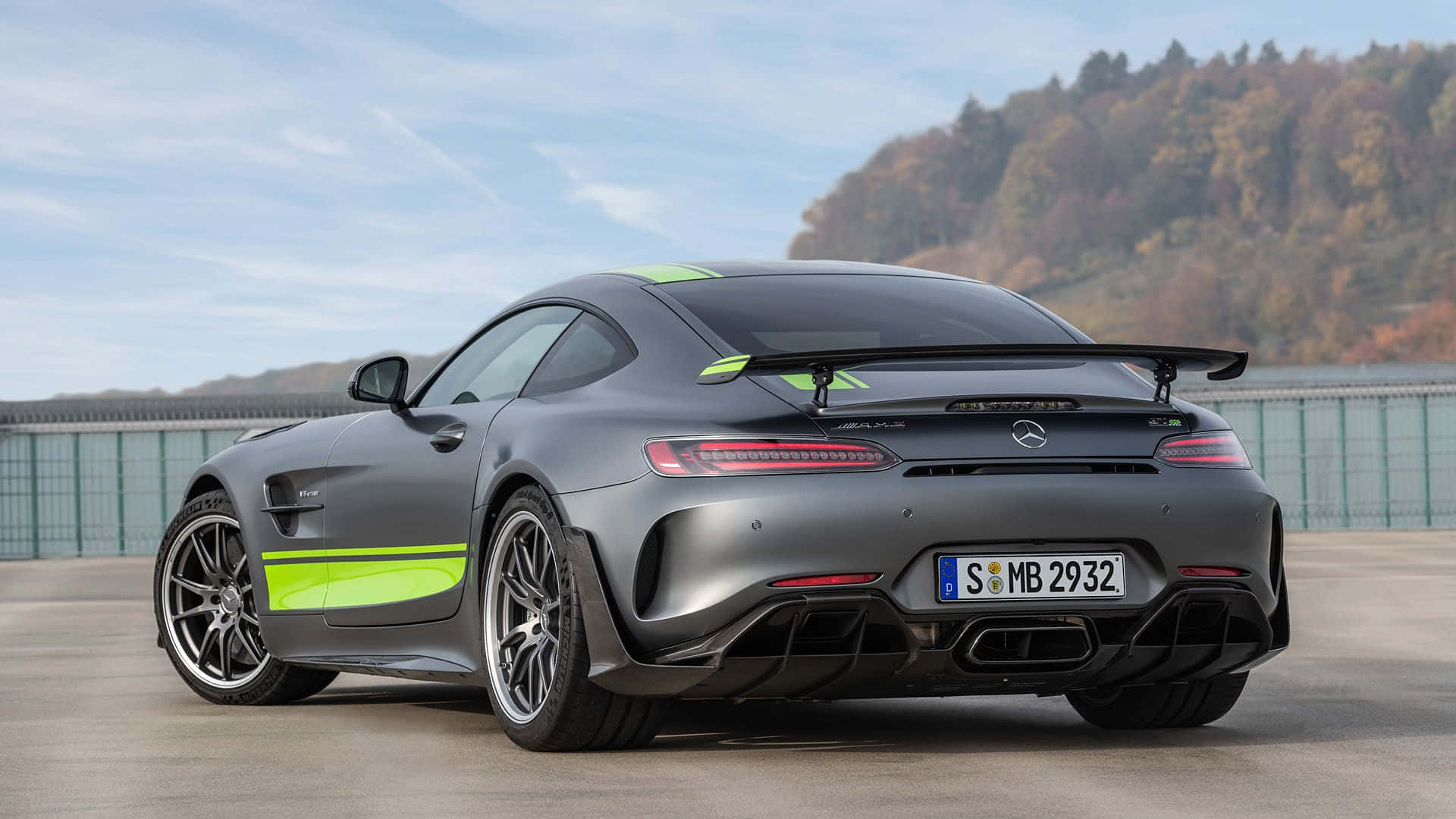 啞光灰色 Mercedes-AMG GT R 帶有螢光綠色條紋，停放在戶外靠近森林山坡處。