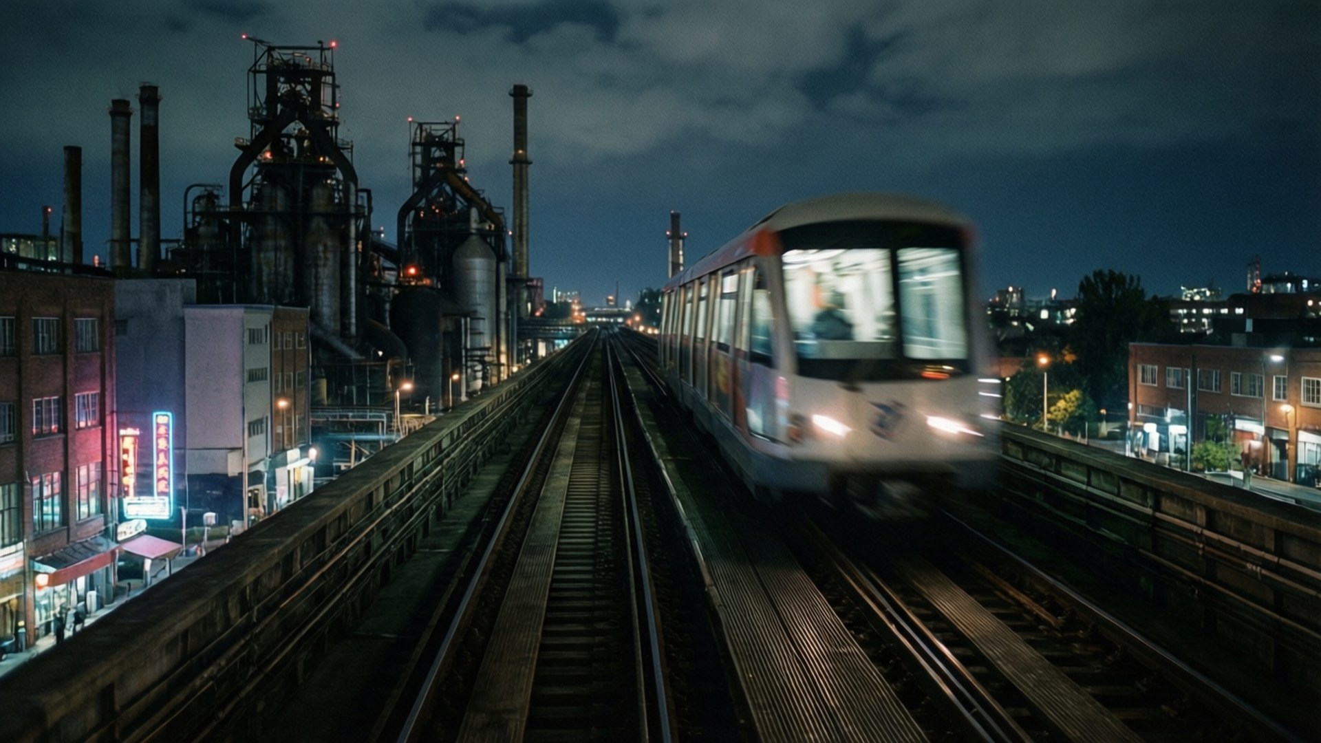 夜間在高架軌道上快速行駛的火車，背景有工業建築和城市燈光