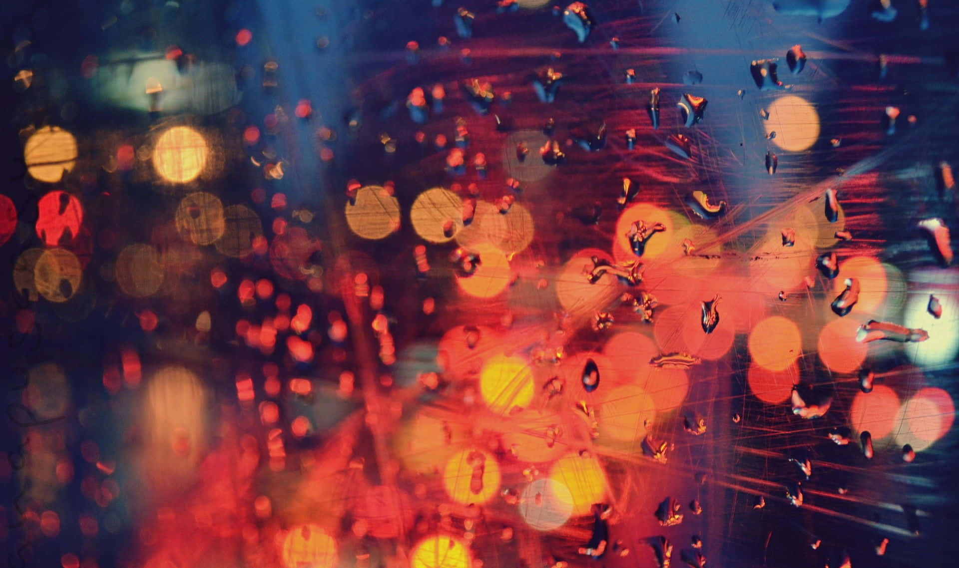 窗戶上的雨滴將城市燈光模糊成夜間色彩繽紛的散景。
