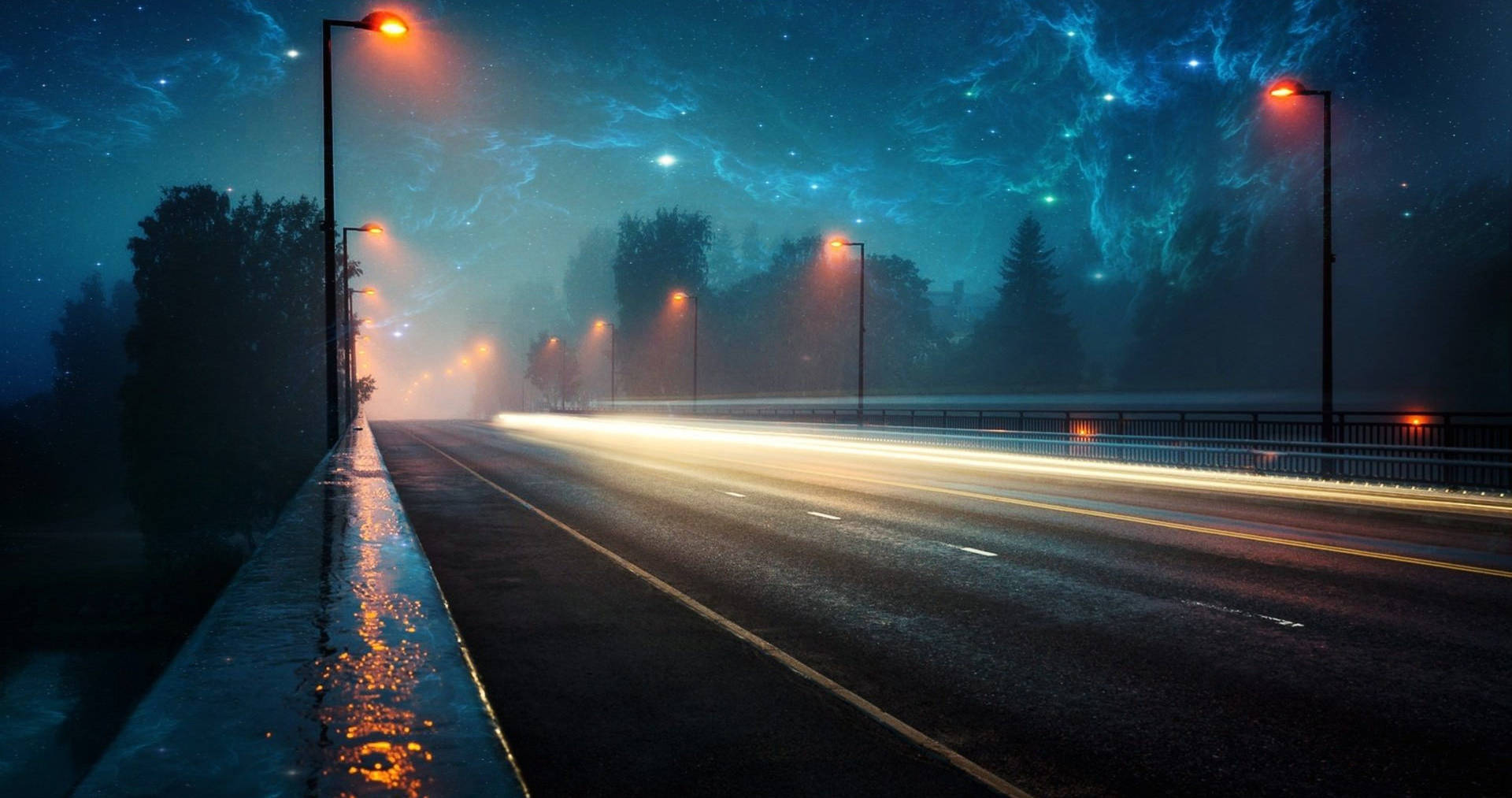 夜色空橋 Chromebook 美學壁紙 壁紙 — 霧氣瀰漫的夜晚道路，在發光路燈下，有汽車燈光的條紋和星光閃爍的電藍色天空。