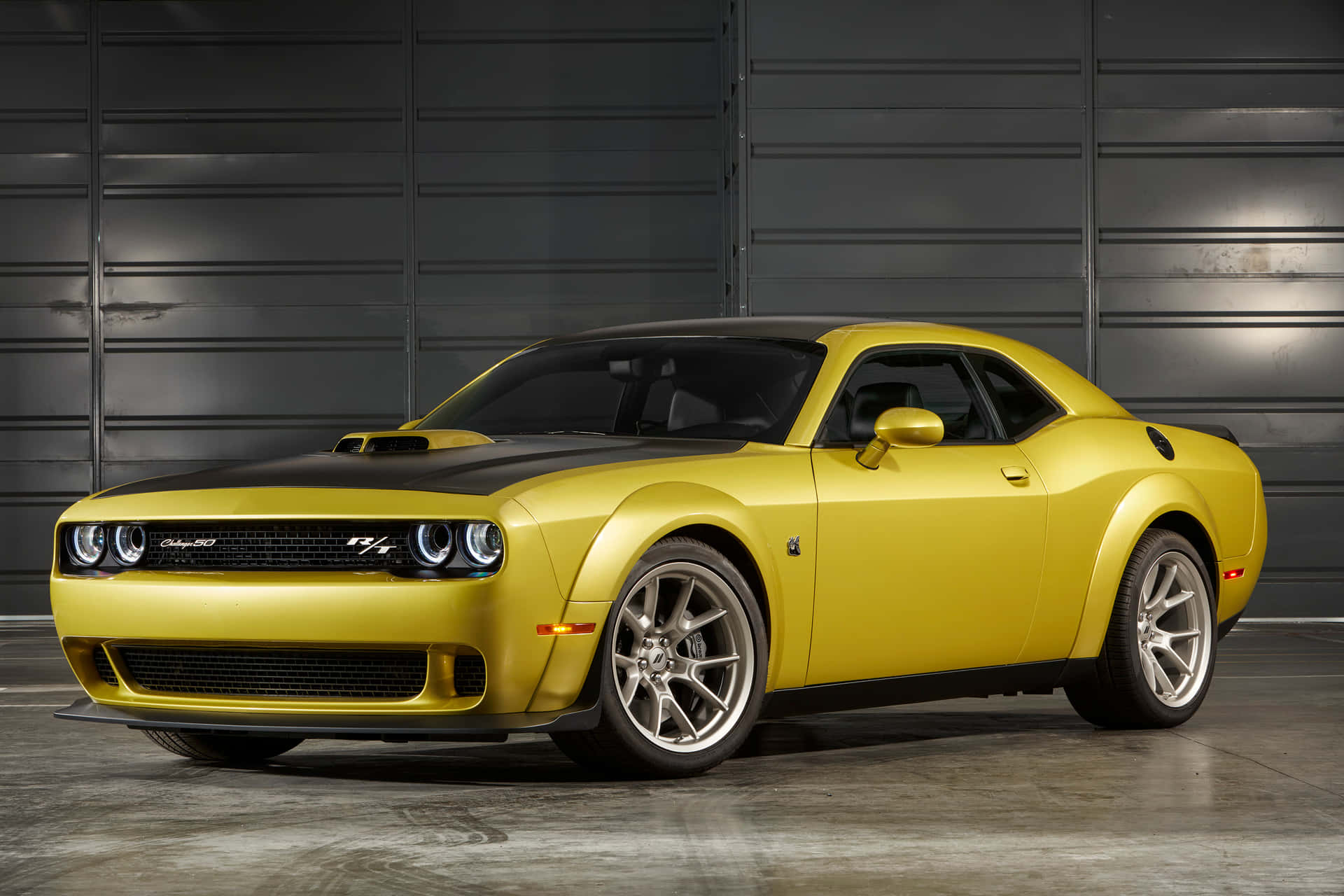 黃色 Dodge Challenger RT 跑車，在現代車庫中帶有黑色引擎蓋條紋。