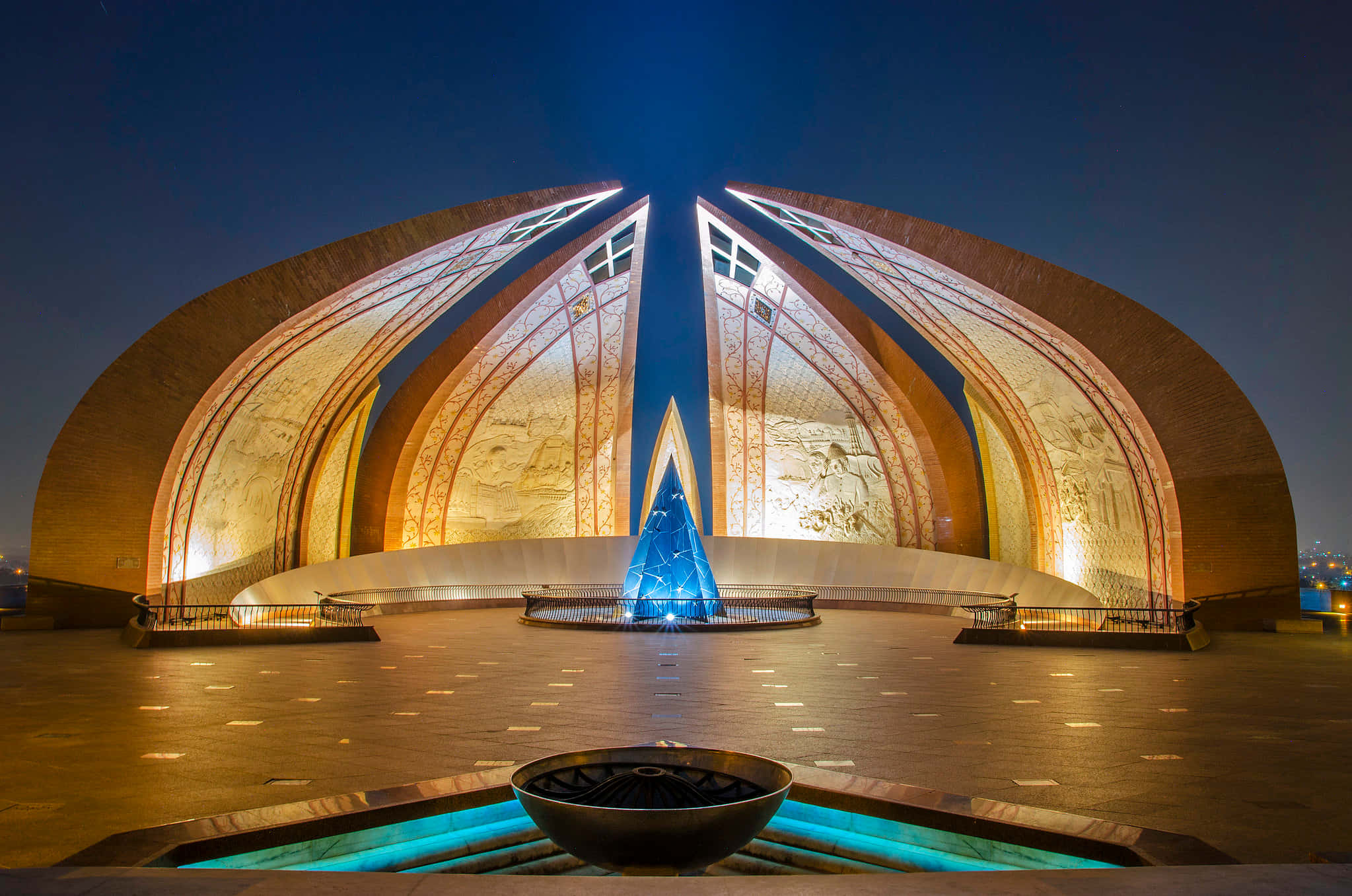 Pakistan 桌布 壁紙 — 夜間一座宏偉的照明建築紀念碑，擁有彎曲的拱門和發光的藍色噴泉。