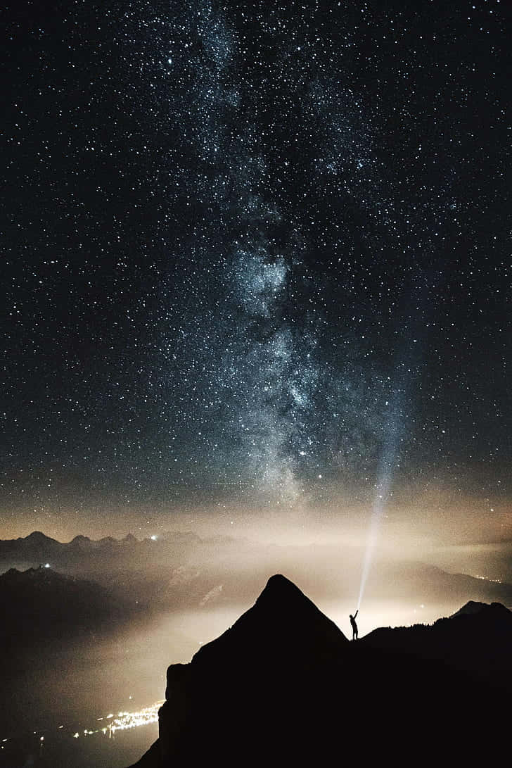 山頂上的人將手電筒照向星空
