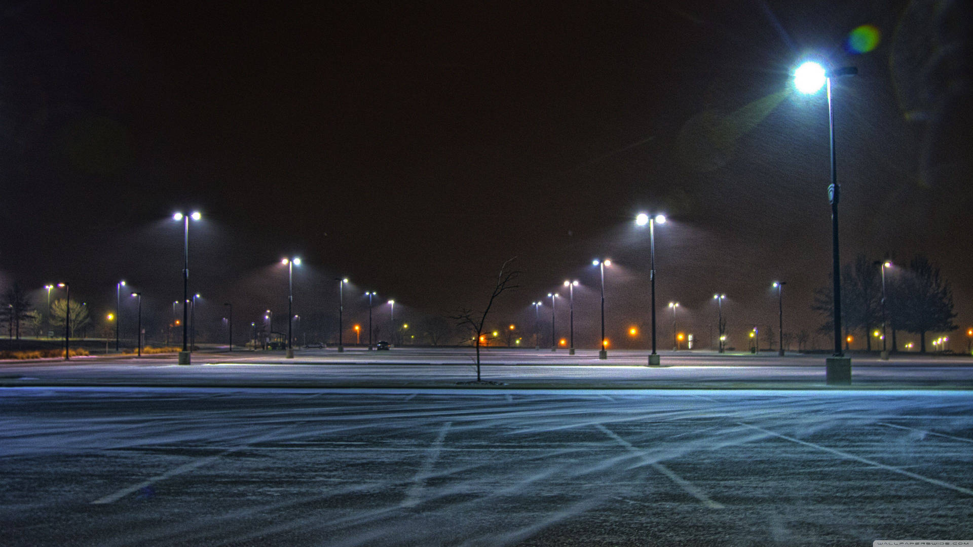 白雪覆蓋的空停車場，夜晚被街燈照亮