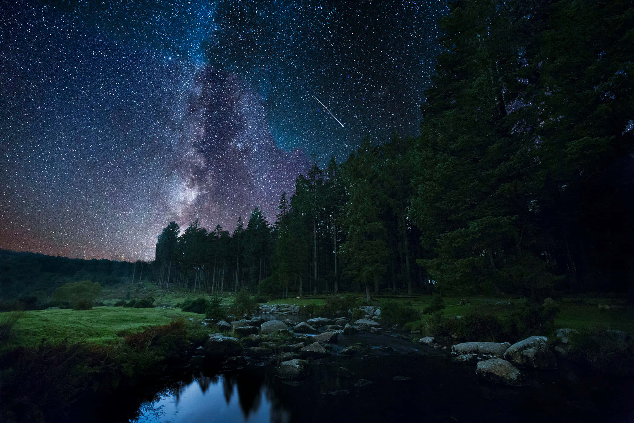 夜間城市景觀 壁紙 — 繁星點點的夜空，銀河與流星在黑暗森林和倒映宇宙的平靜河流上方拱起。