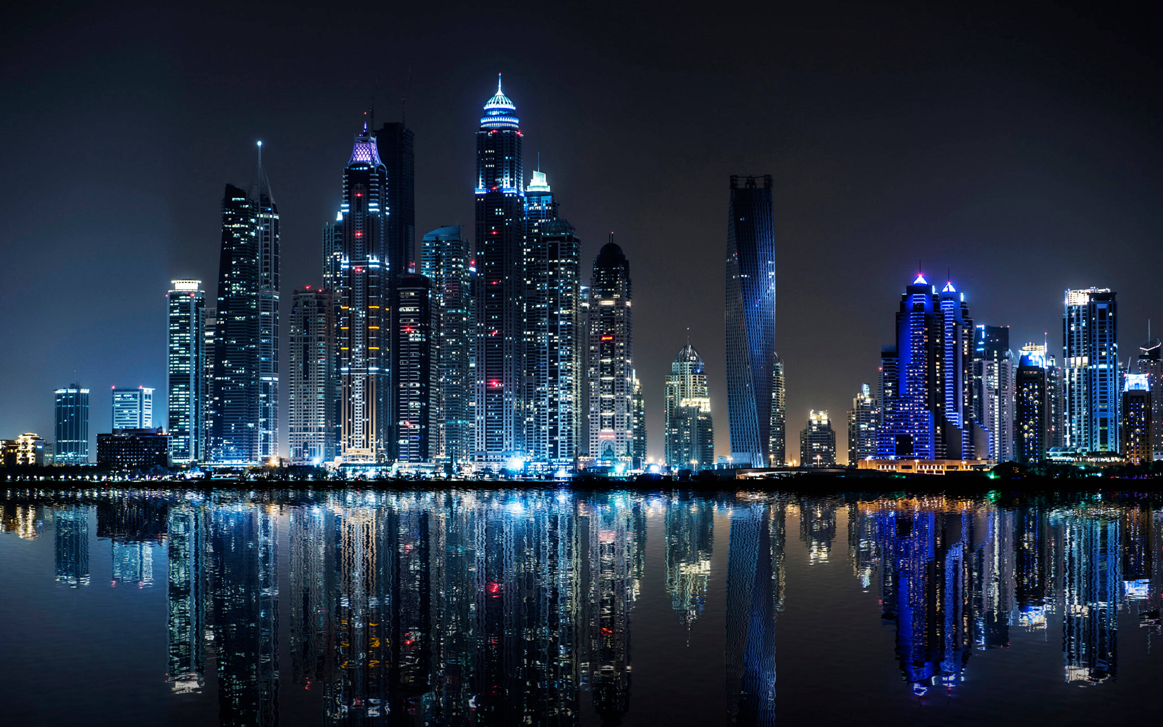 夜間城市景觀專業桌面壁紙 壁紙 — 令人目眩的夜景城市景觀，高聳的摩天大樓的藍色和白色燈光完美地倒映在平靜的水面上。