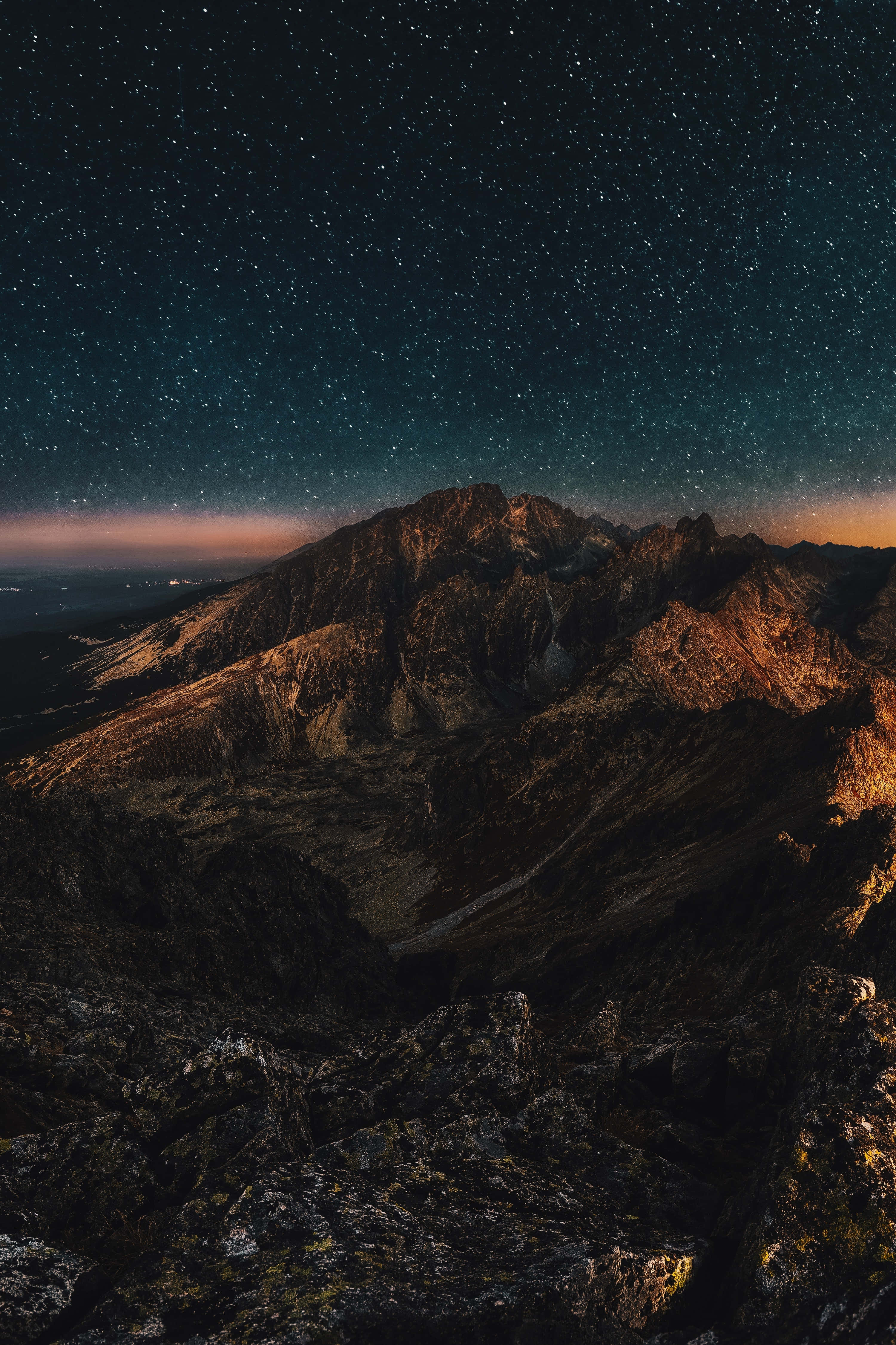 夜間山景手機背景 壁紙 — 在密集的星幕下，雄偉的山脈沐浴在溫暖的暮光中。