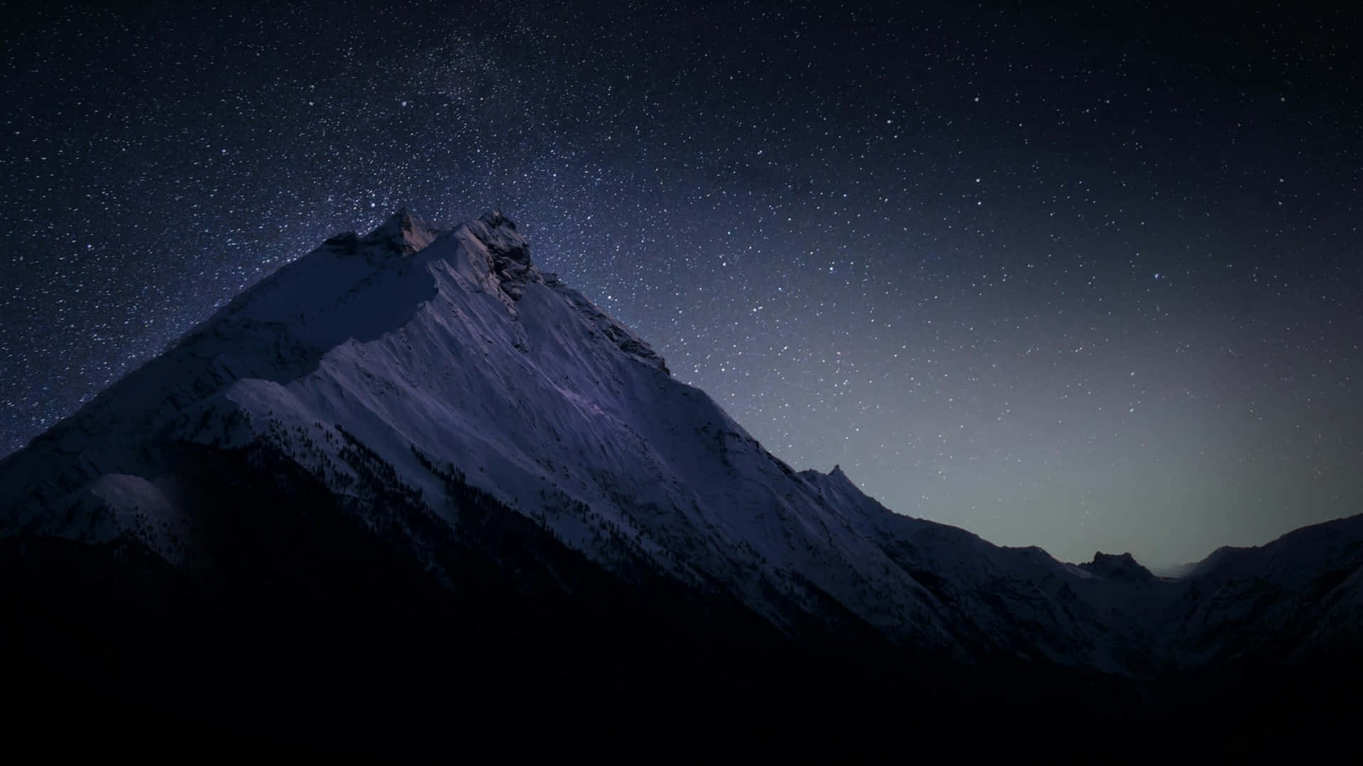 繁星點點的夜空下，白雪覆蓋的山峰與銀河系。