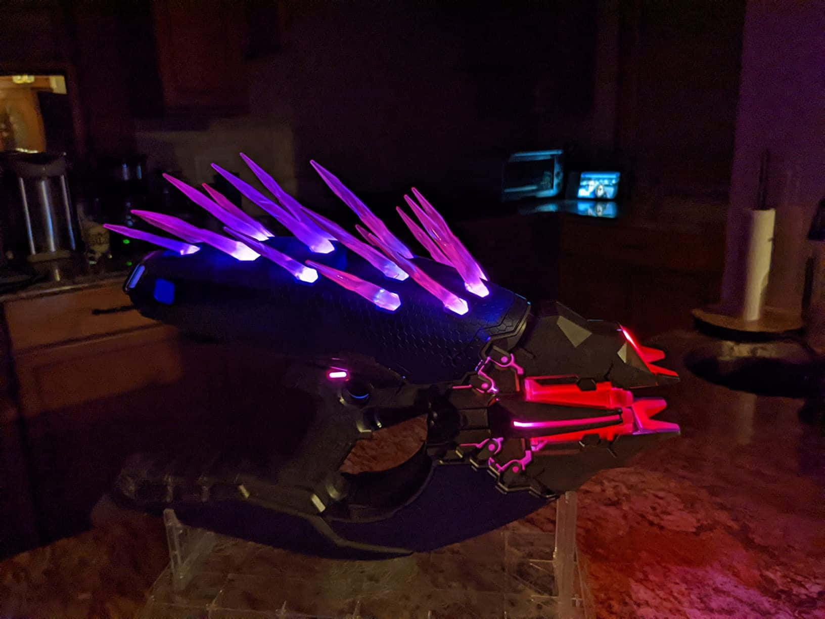 Halo Needler 桌布 壁紙 — 夜間廚房枱面上展示的發光紫色和紅色未來武器，帶有尖刺燈光。