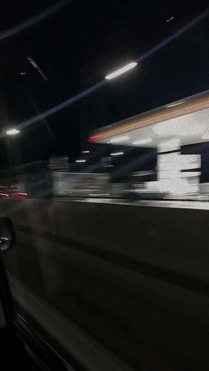 夜間駕車經過加油站，車窗外的燈光掠過。