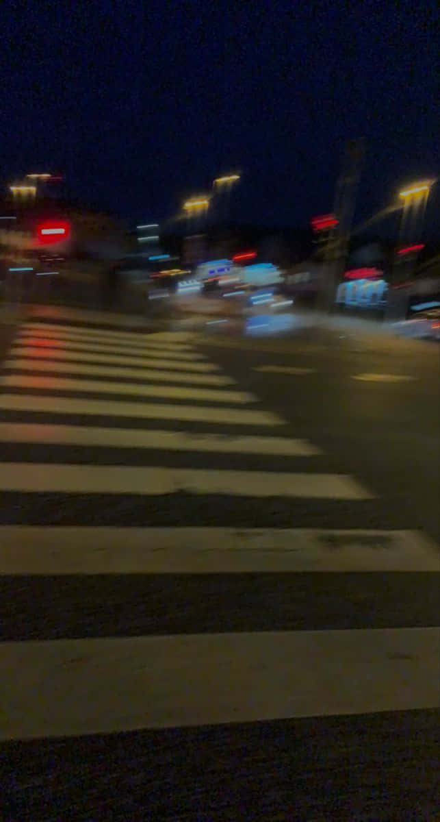 夜晚街道，模糊車燈與街燈下的行人過路處。