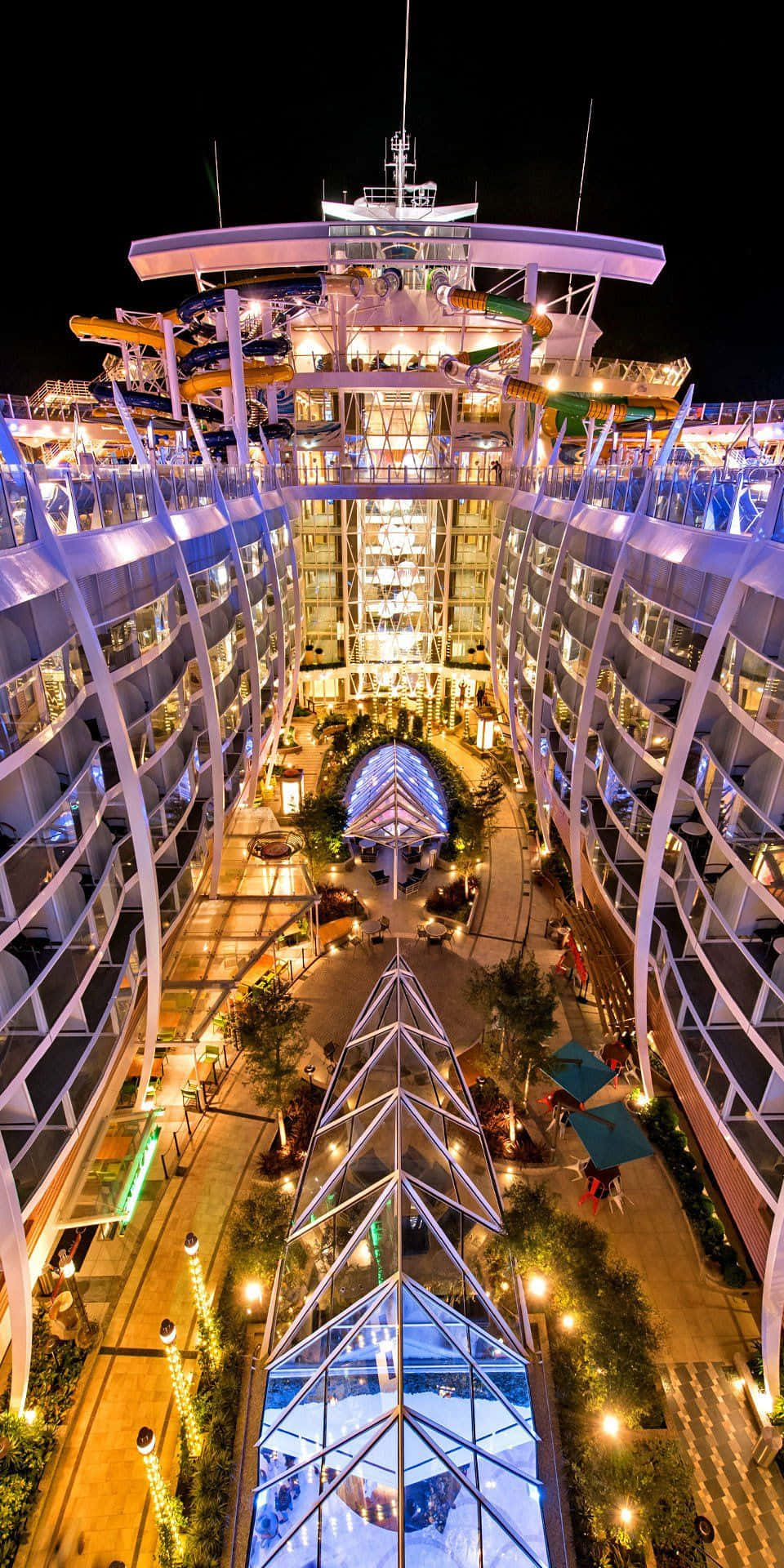 夜間泳池郵輪 壁紙 — 一艘巨大照明遊輪的夜間空中景觀，設有發光甲板、水上滑梯和中央中庭。