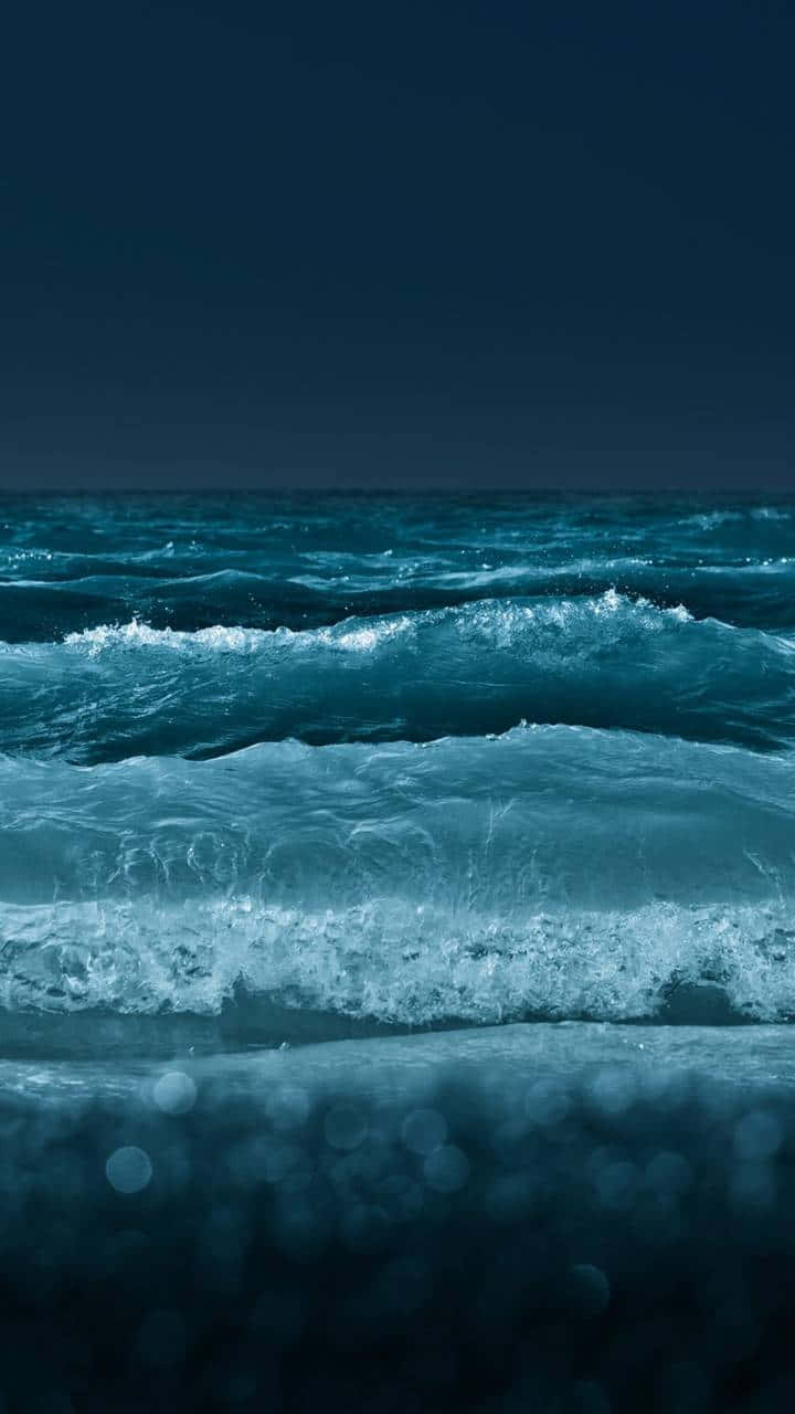 夜間海浪翻滾，前景有散景燈光