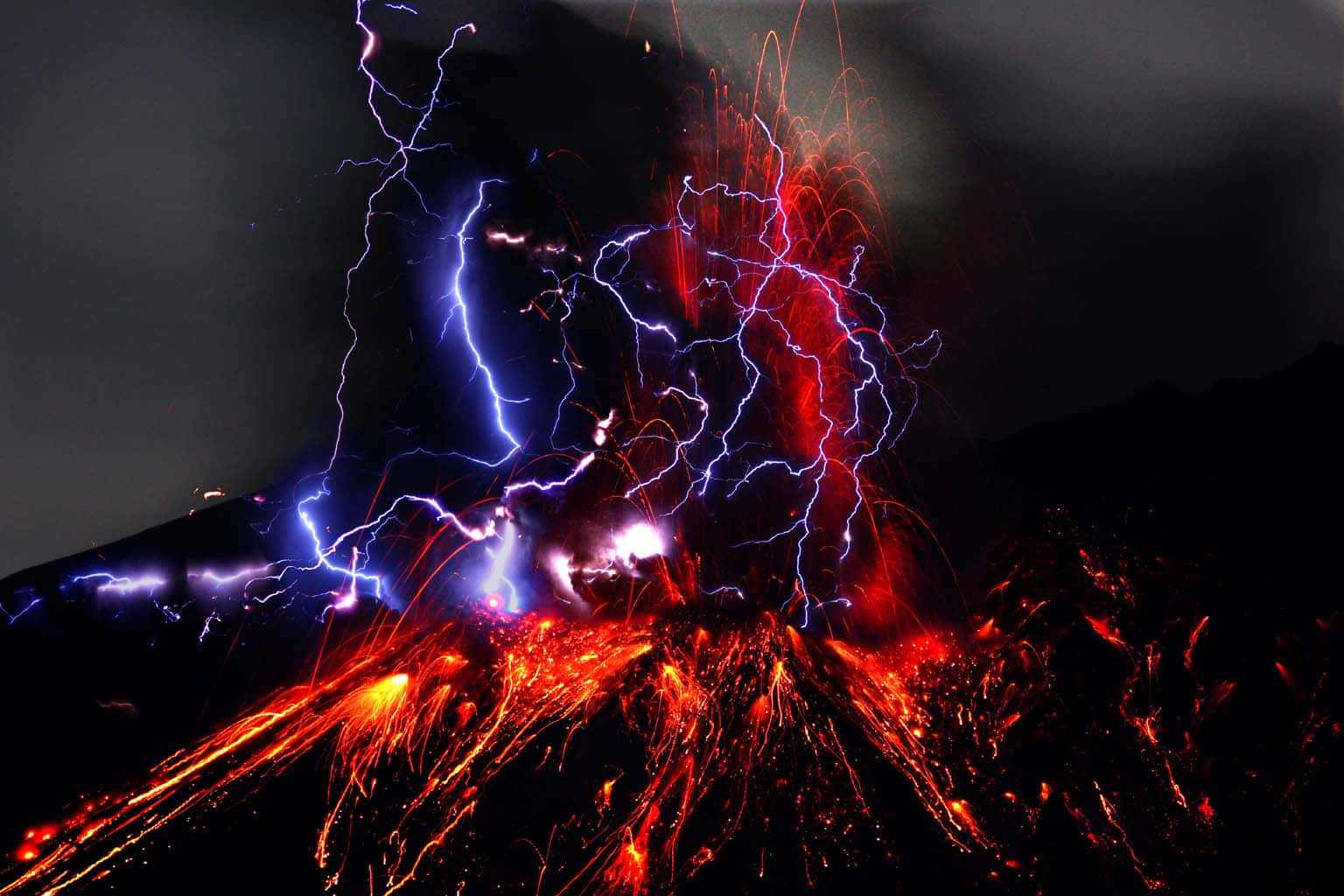 Red Lightning 桌布 壁紙 — 夜間火山爆發，鮮紅色熔岩噴泉和藍色閃電照亮黑暗的天空。