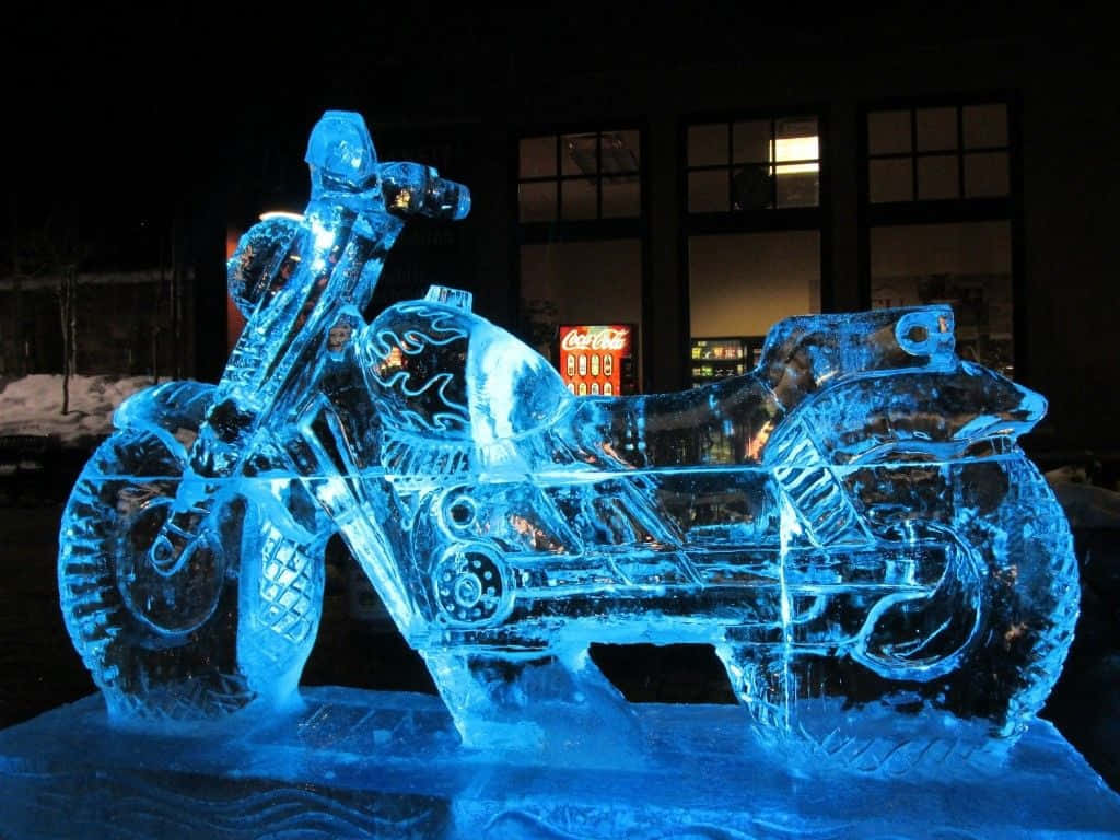 Ice Sculpture 桌布 壁紙 — 夜間發光的藍色冰雕電單車，地上有雪，後面有亮燈的建築物。