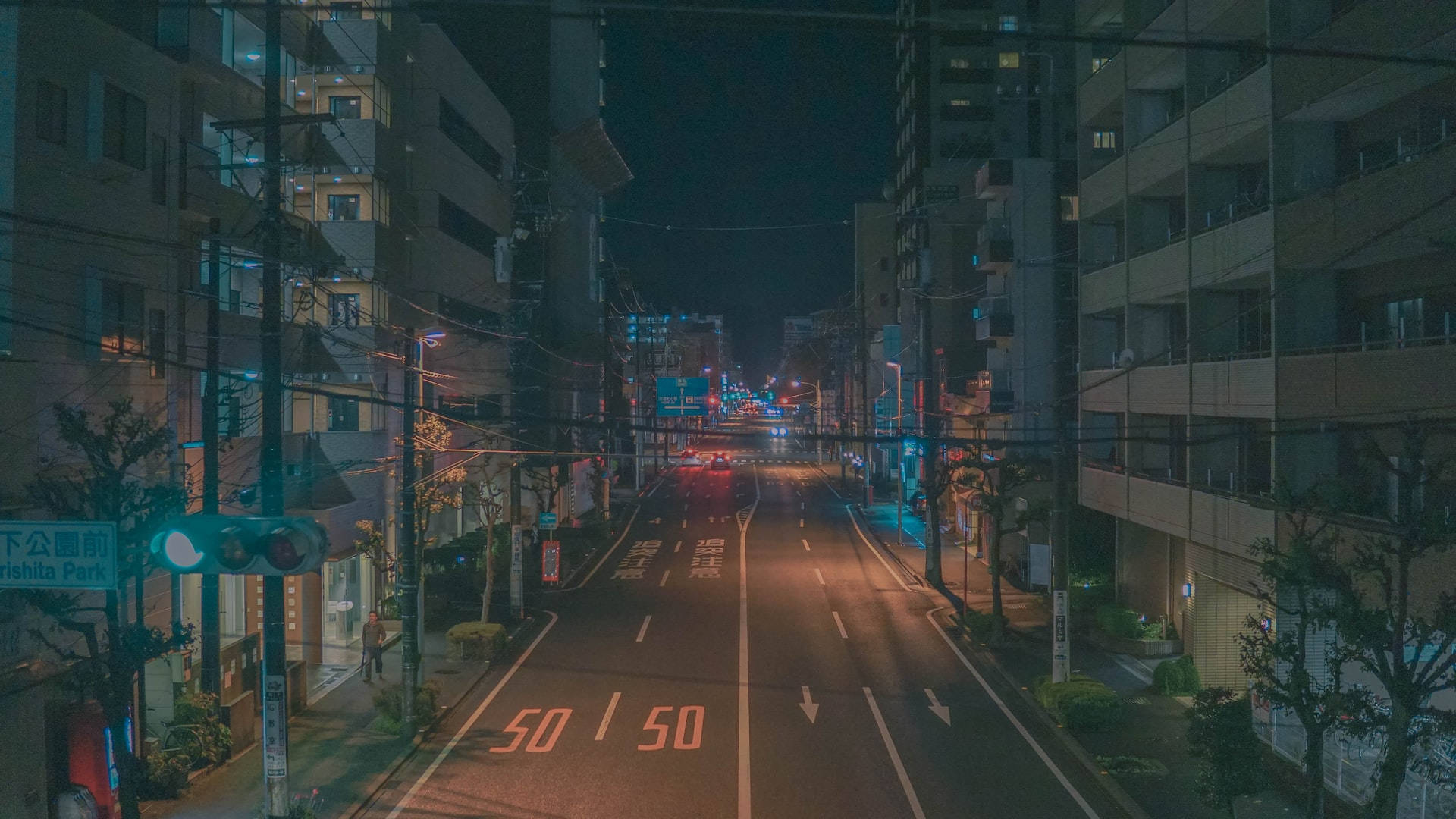 夜晚的城市街道，發光的街燈和遠處的車燈在高樓之間。
