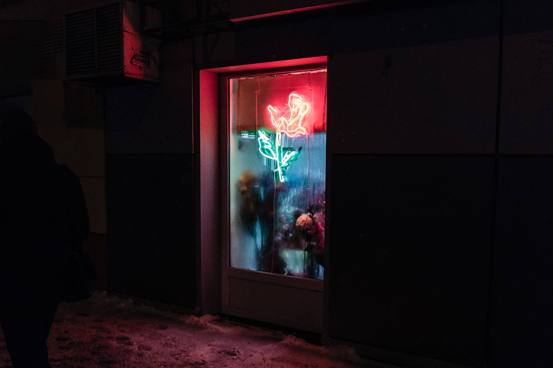 霓虹玫瑰標誌在雪夜的城市商店櫥窗中閃耀。