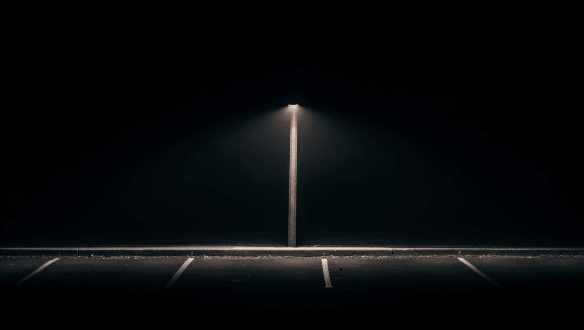 一支孤獨的路燈在夜晚照亮了空蕩蕩的停車場。